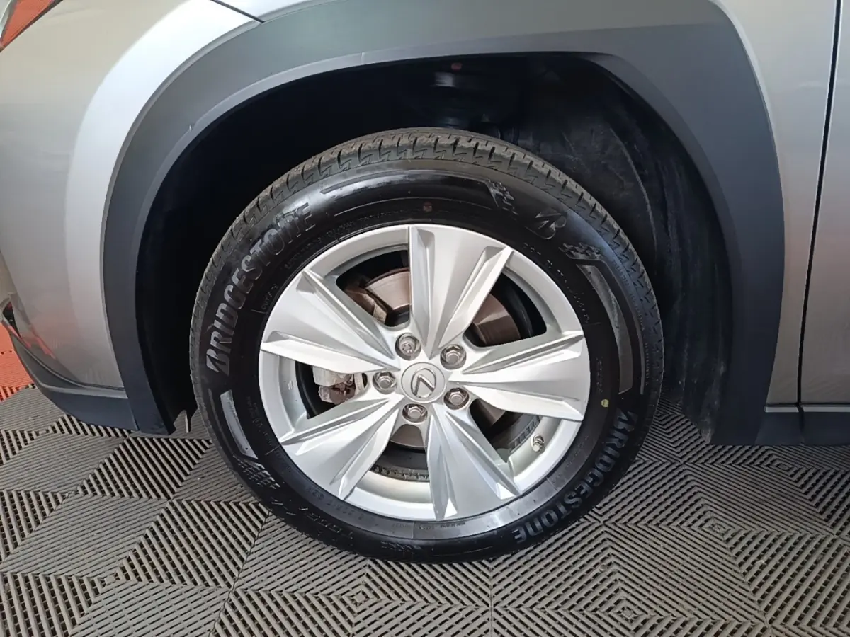 Gros plan sur la roue avant droite d'un Lexus UX 250H gris clair avec jante alliage et pneu Bridgestone.