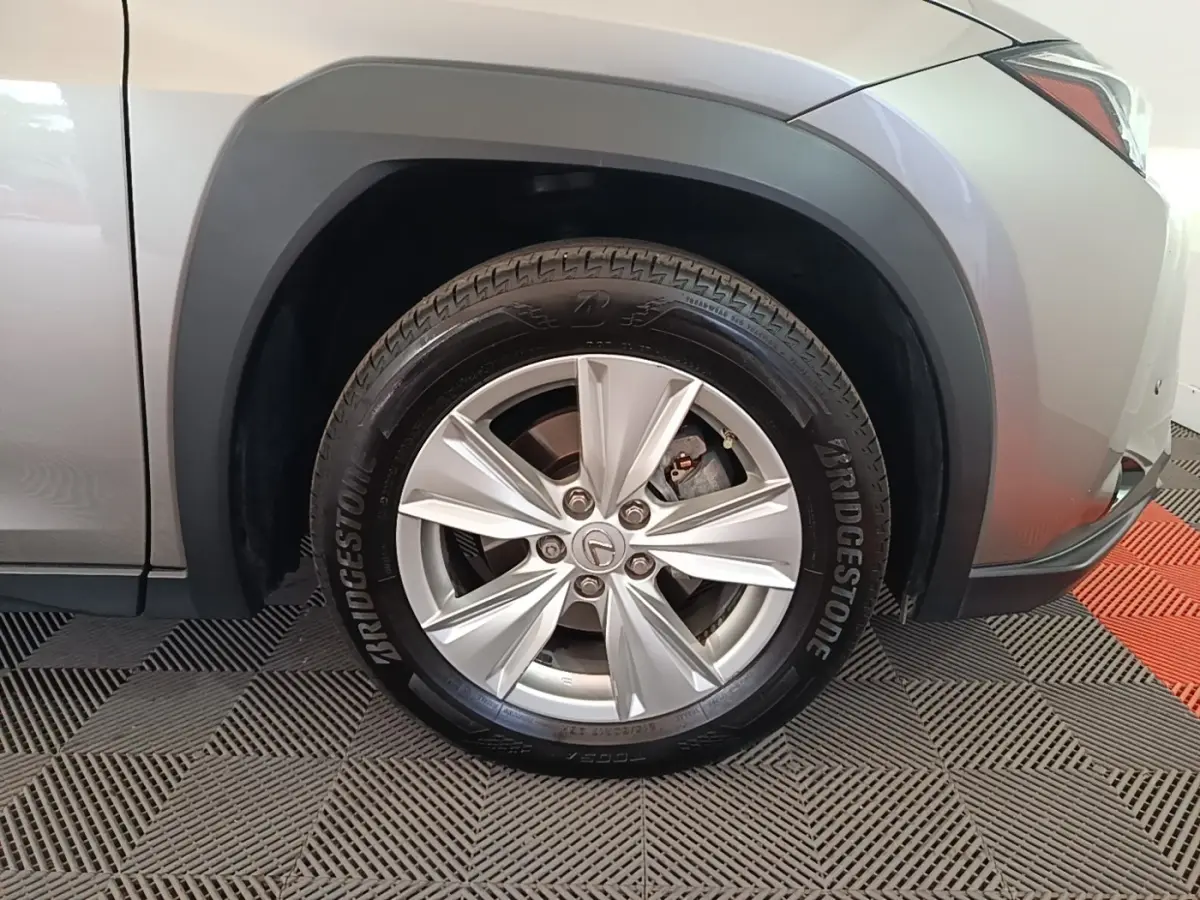 Gros plan sur la roue avant droite grise d’un Lexus UX 250H 2WD avec jante argentée et pneu Bridgestone.