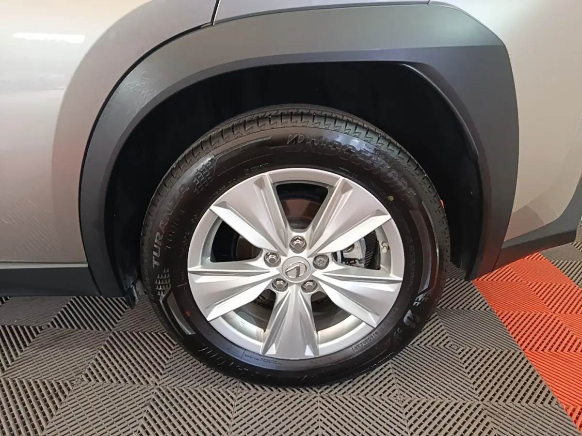 Gros plan sur la roue avant gauche gris clair du Lexus UX 250H 2WD Pack Business avec jante alliage et pneu Bridgestone.