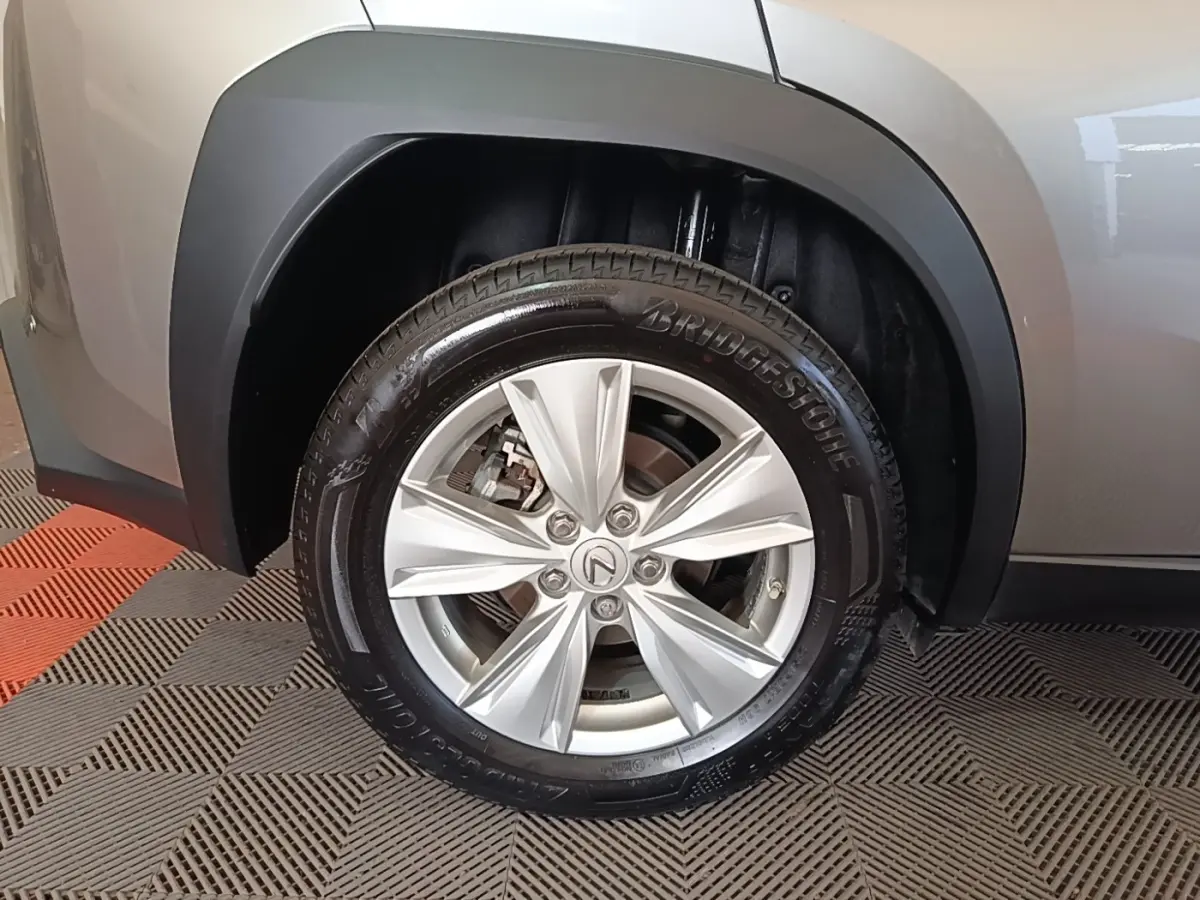 Gros plan sur la roue avant droite gris clair du Lexus UX 250H 2WD Pack Business avec jante alliage et logo Lexus.
