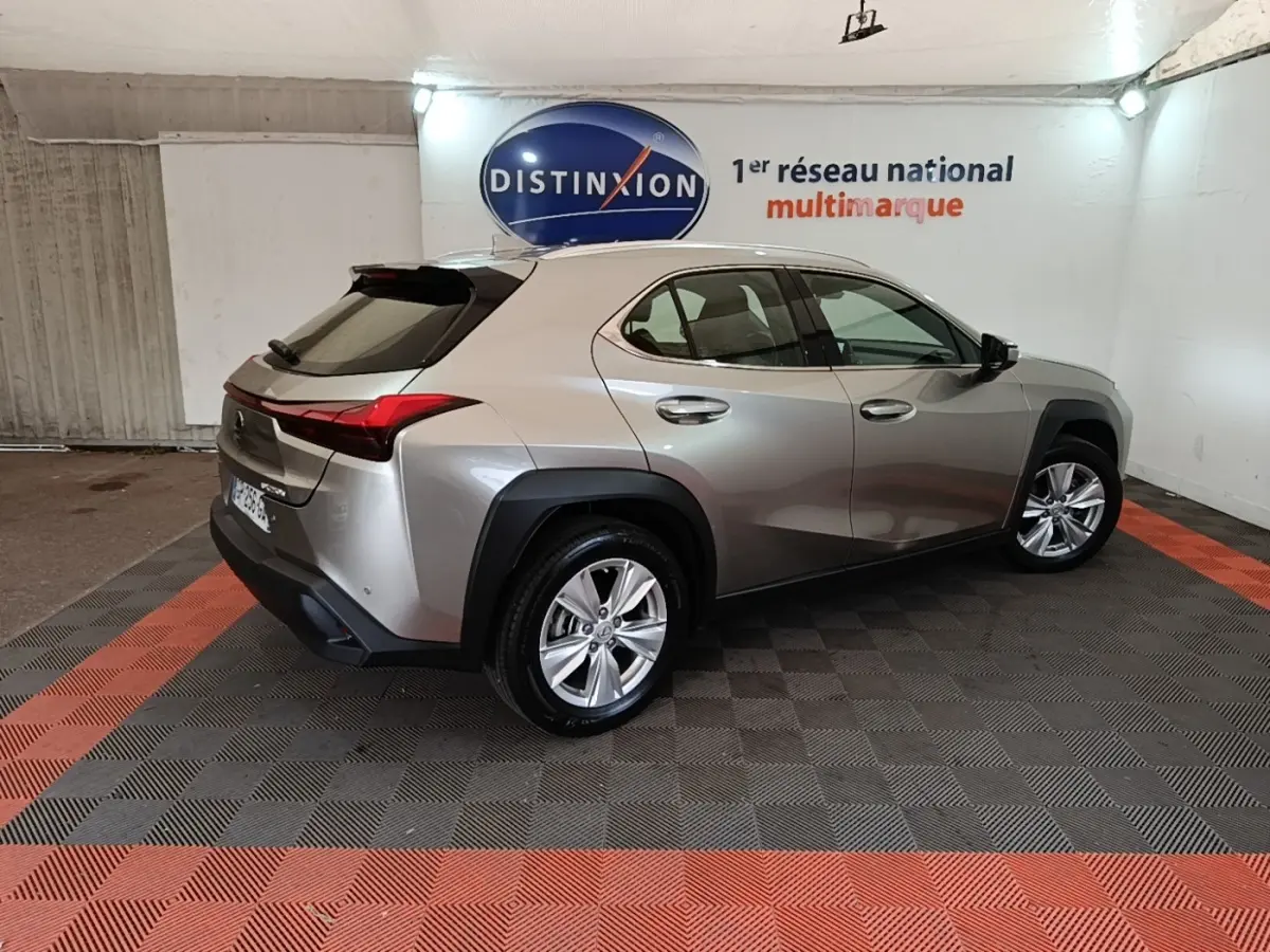 Lexus UX 250H gris clair en vue 3/4 arrière droit, avec feux arrière LED et jantes alliage visibles.
