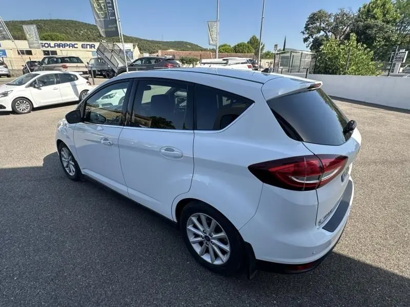 Vue 3/4 arrière droite d'un Ford C-MAX blanc 2017, finition Titanium avec vitres arrière teintées et jantes alliage.