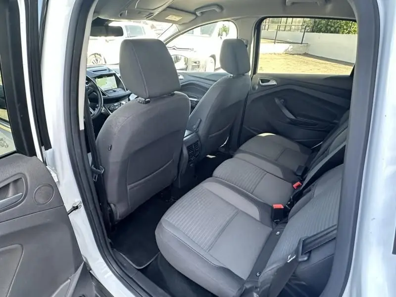 Vue intérieure côté gauche arrière du Ford C-MAX blanc 2017, montrant les sièges arrière et l'avant du véhicule.