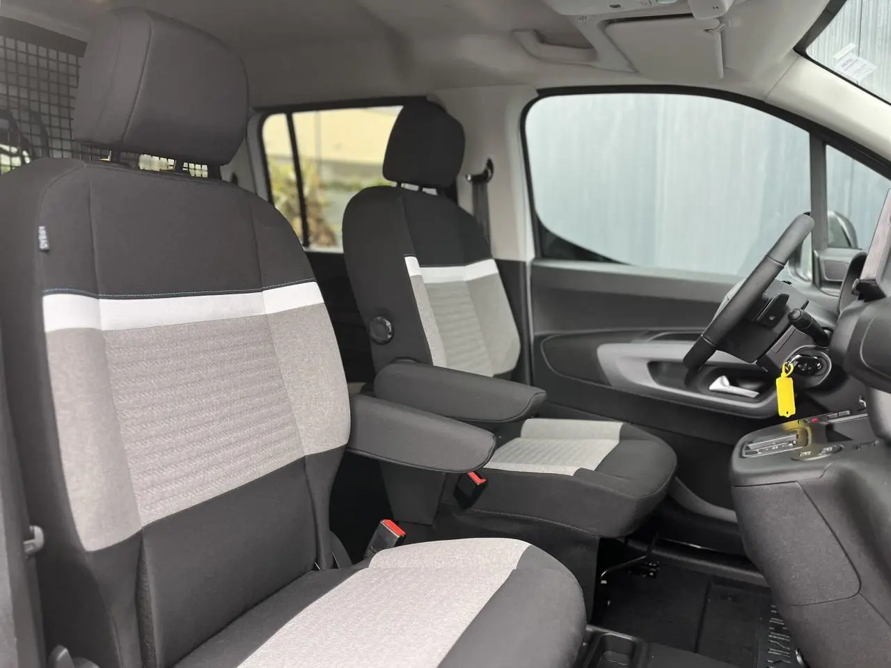 Vue intérieure côté conducteur du Citroën Berlingo Multispace 2025, sièges tissu bicolore avec accoudoirs et volant multifonctions.