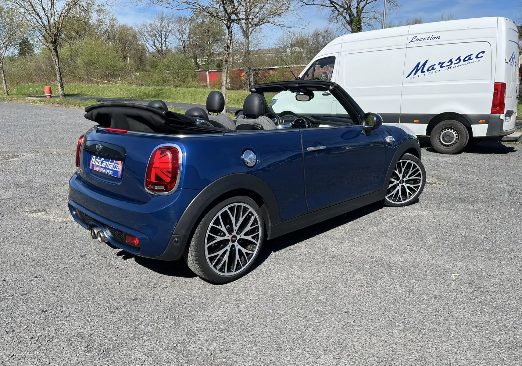 Vue 3/4 arrière droite d'une MINI Cabriolet bleu avec capote noire baissée et feux arrière Union Jack.