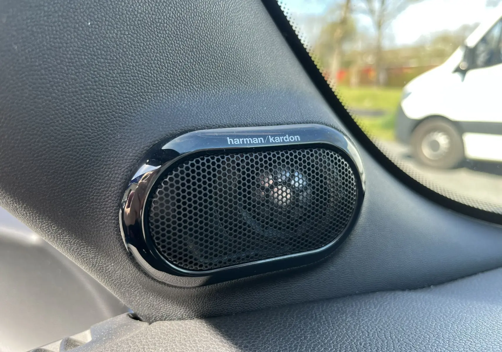 Gros plan sur l'enceinte Harman/Kardon noire intégrée à l'intérieur d'une MINI Cabriolet F57 bleu, côté droit près du pare-brise.