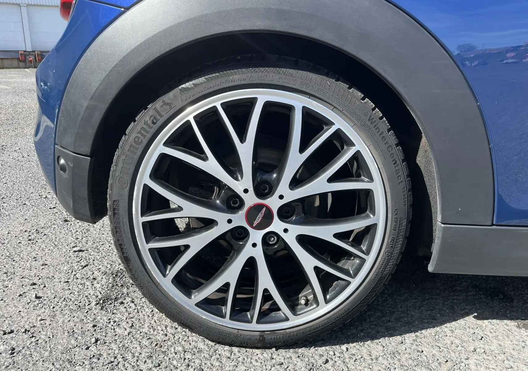 Gros plan sur la roue arrière droite avec jante alliage noire et argentée de la MINI Cabriolet bleu John Cooper Works.