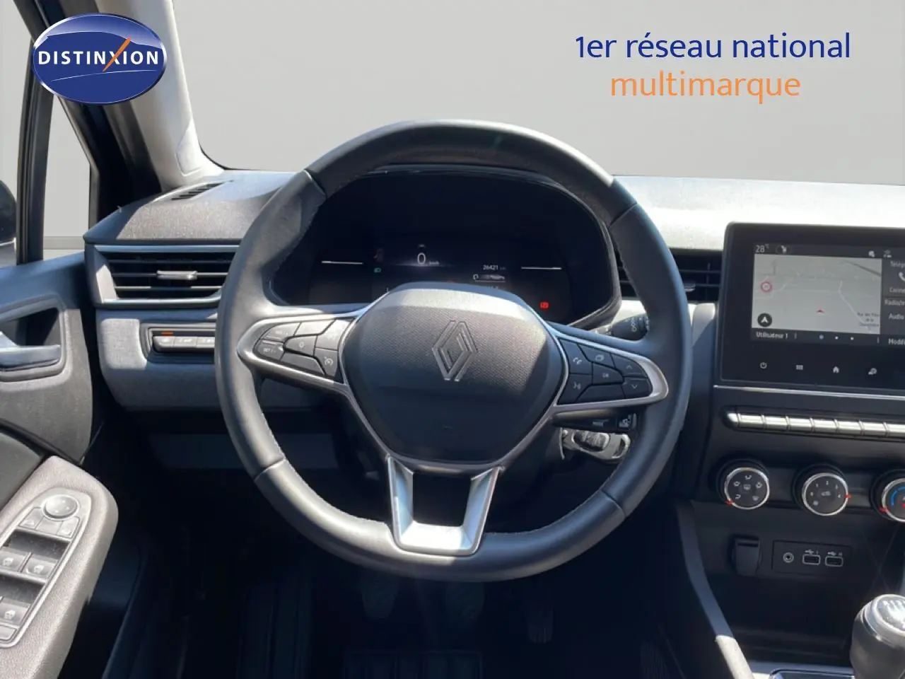 Vue intérieure centrée sur le volant Renault Clio 2025, tableau de bord numérique et écran tactile moderne.