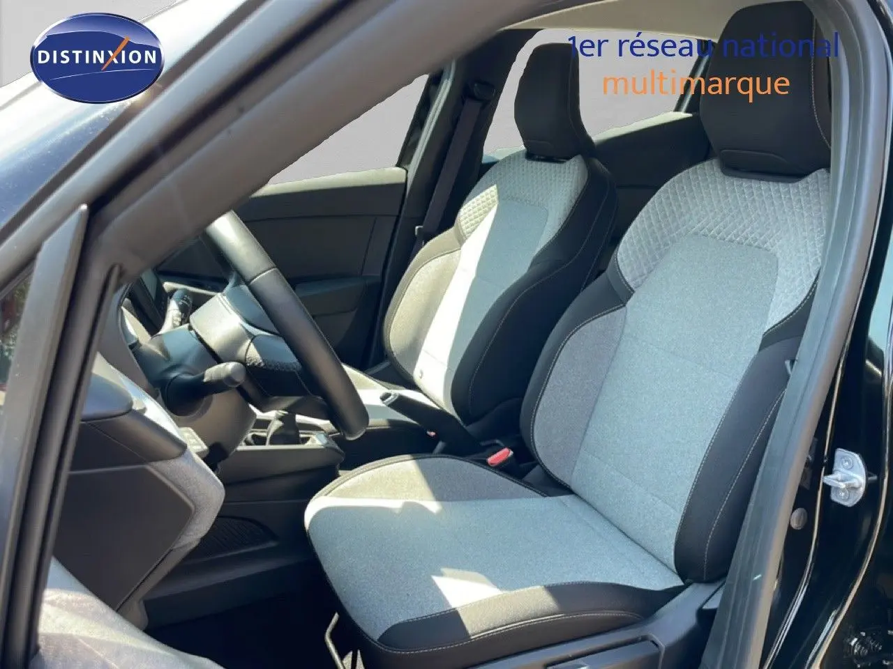 Vue intérieure côté conducteur de la Renault Clio V BluedCi 100ch Evolution 2025 avec sièges tissu gris et noir étoile métal.