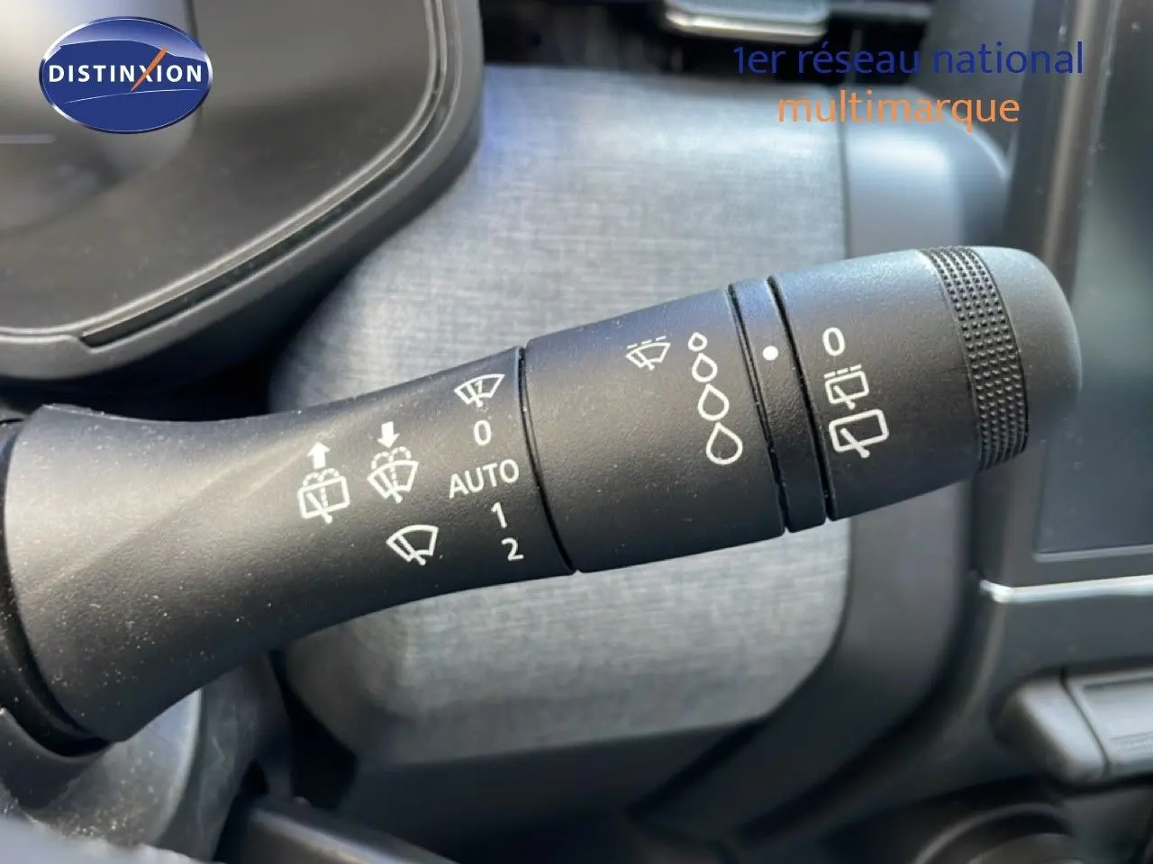 Gros plan sur la manette de commande des essuie-glaces dans l’habitacle d’une Renault Clio noire étoile métal.