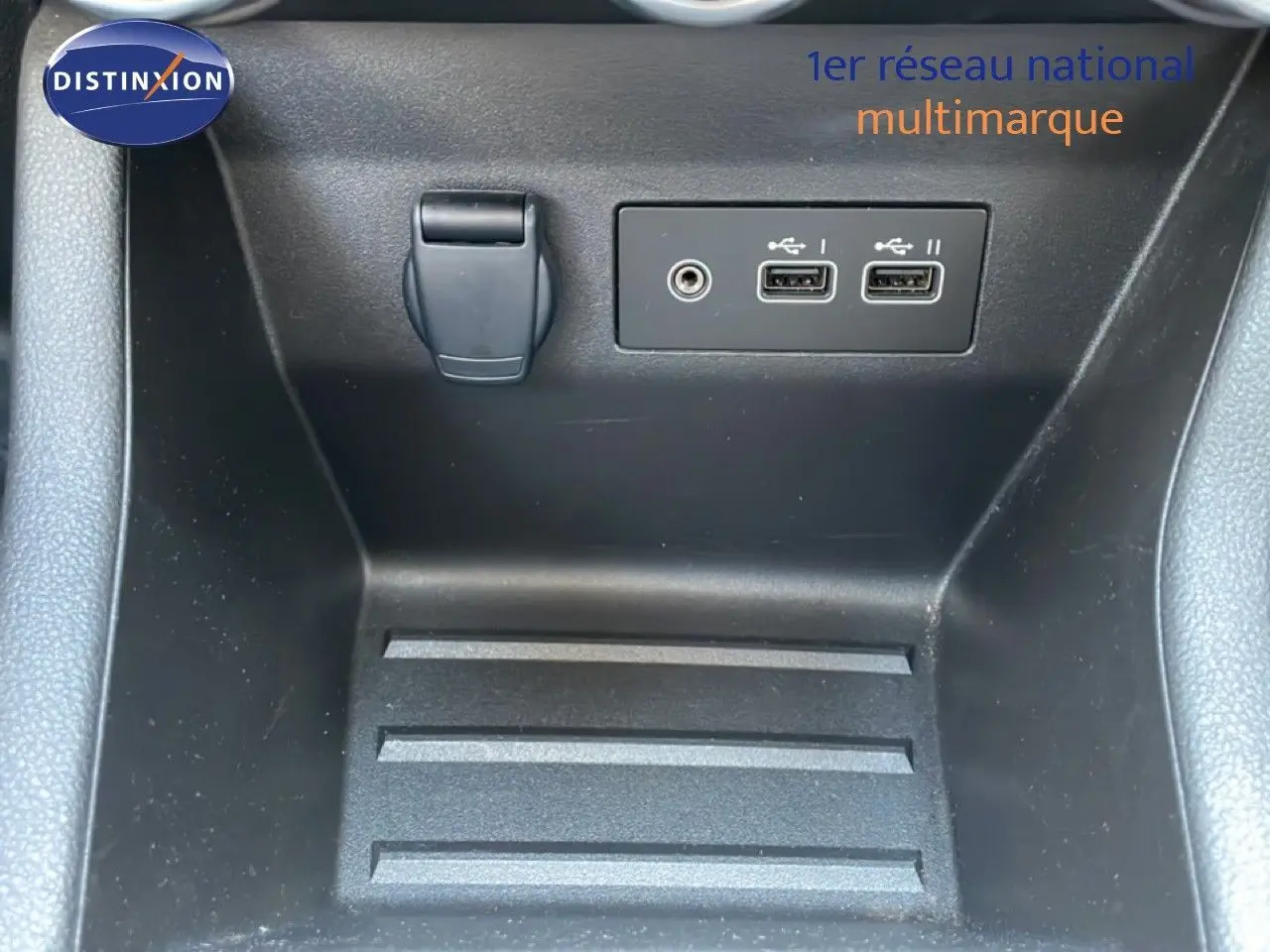 Gros plan sur la console centrale d'une Renault Clio noire, montrant deux ports USB et une prise jack.