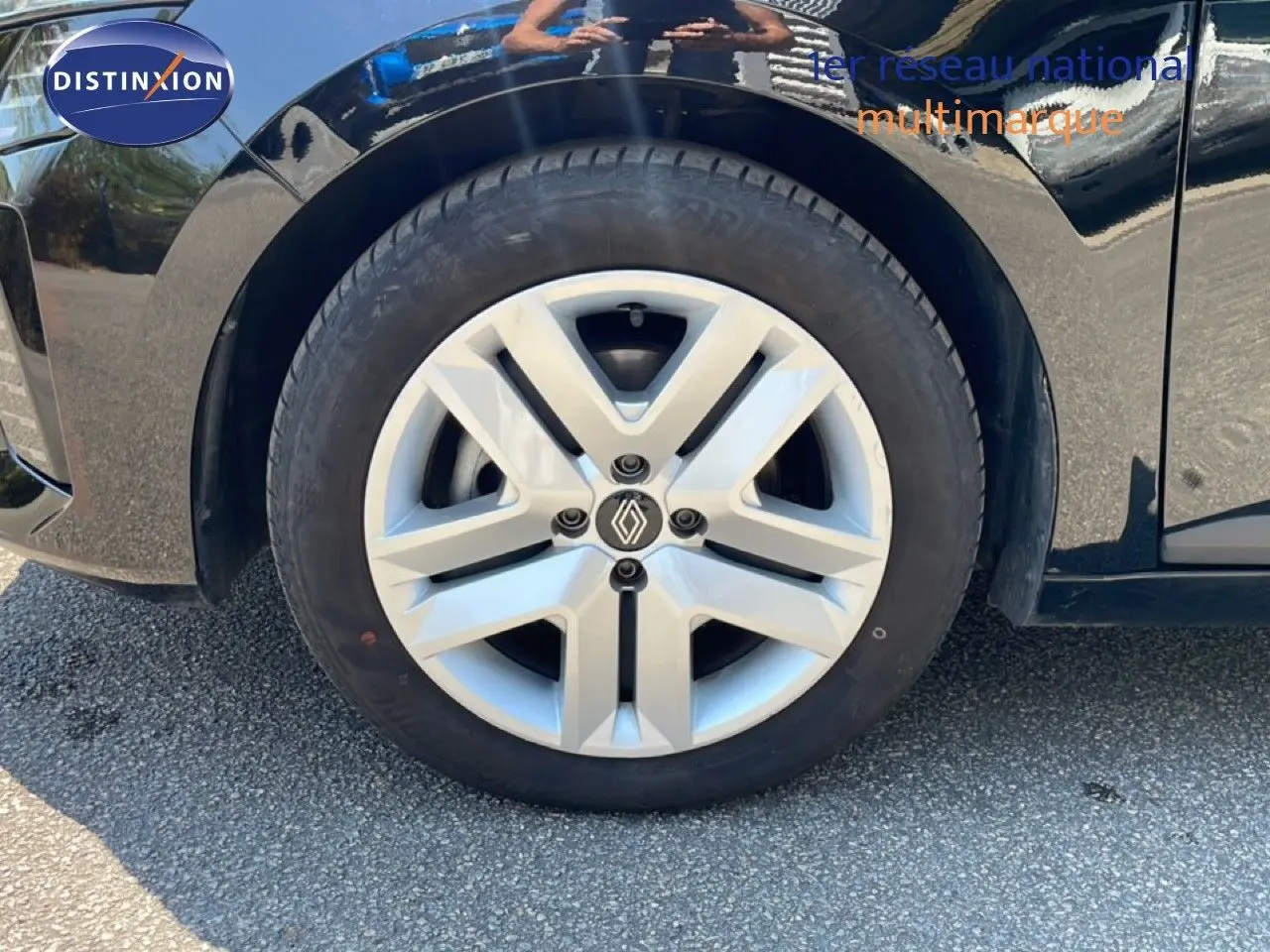 Gros plan sur la roue avant gauche d'une Renault Clio noire étoile métal, mettant en valeur la jante argentée au design moderne.