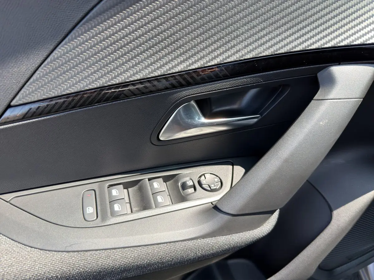 Gros plan sur la porte côté conducteur du Peugeot 2008 gris clair, montrant les commandes des vitres et le bouton de verrouillage.