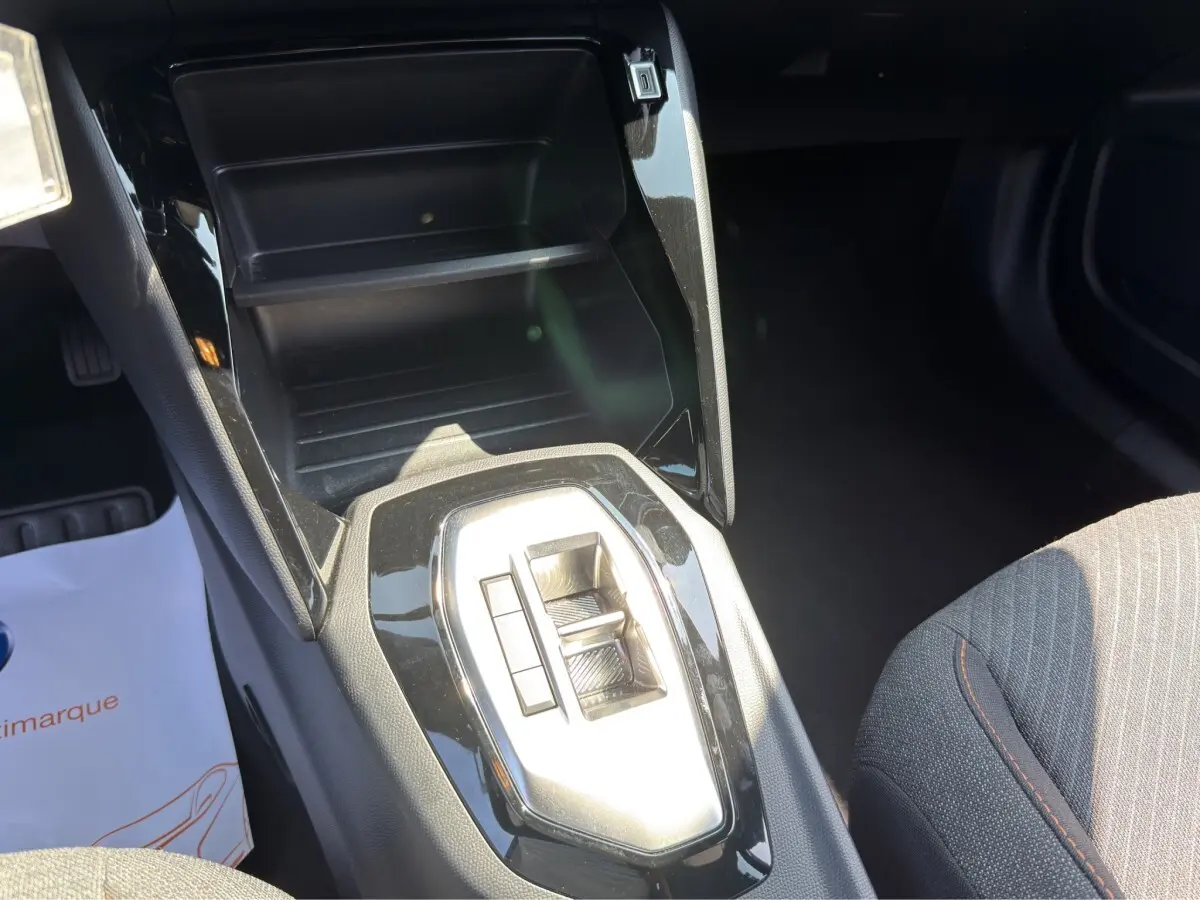 Gros plan sur la console centrale noire brillante et le levier de vitesses automatique dans l’habitacle du Peugeot 2008 gris clair.