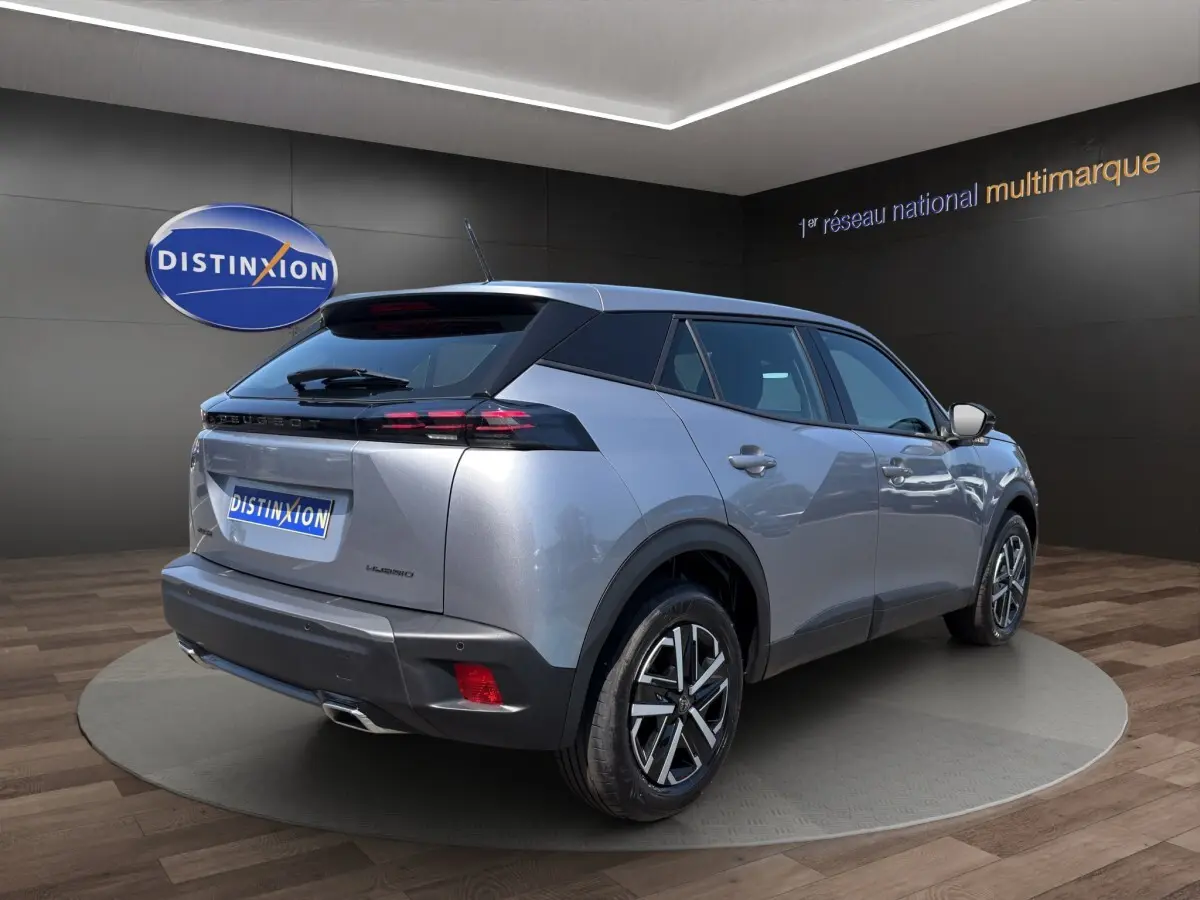 Vue 3/4 arrière droite d'un Peugeot 2008 Hybrid gris clair avec feux arrière LED et jantes alliage bicolores.