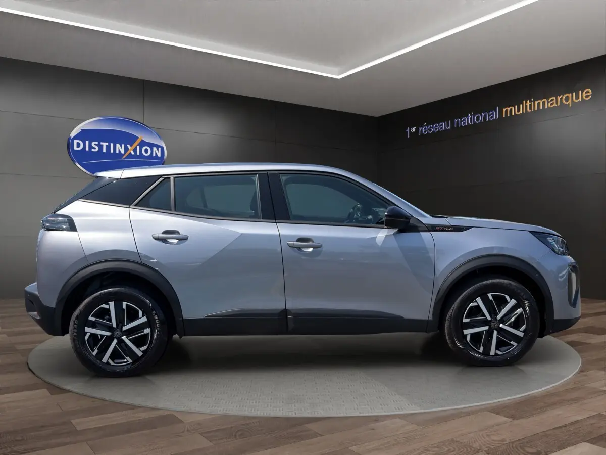 Vue de profil côté gauche d’un Peugeot 2008 Hybrid 145 gris clair avec jantes noires et détails noirs contrastants.