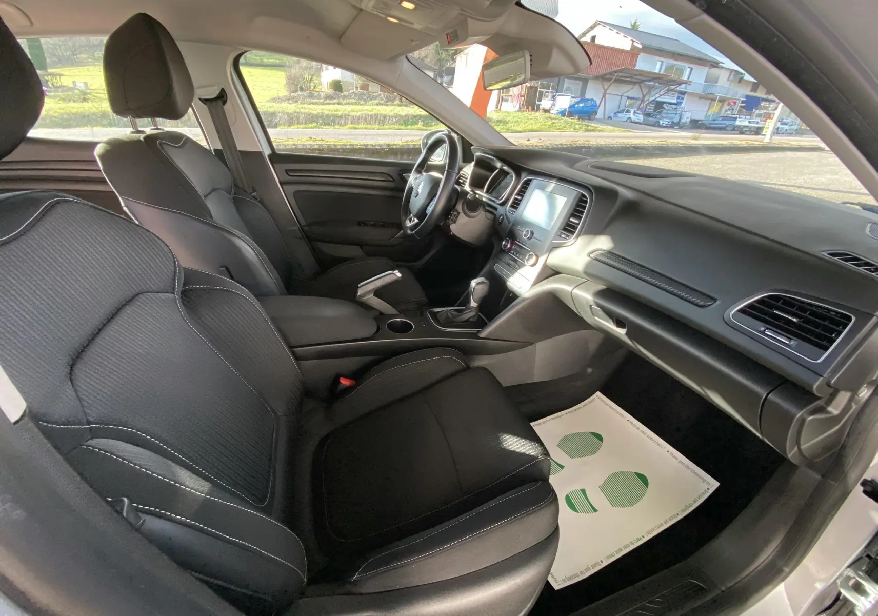 Intérieur noir de la Renault Mégane IV Berline 2020, vue côté passager montrant sièges et tableau de bord moderne.