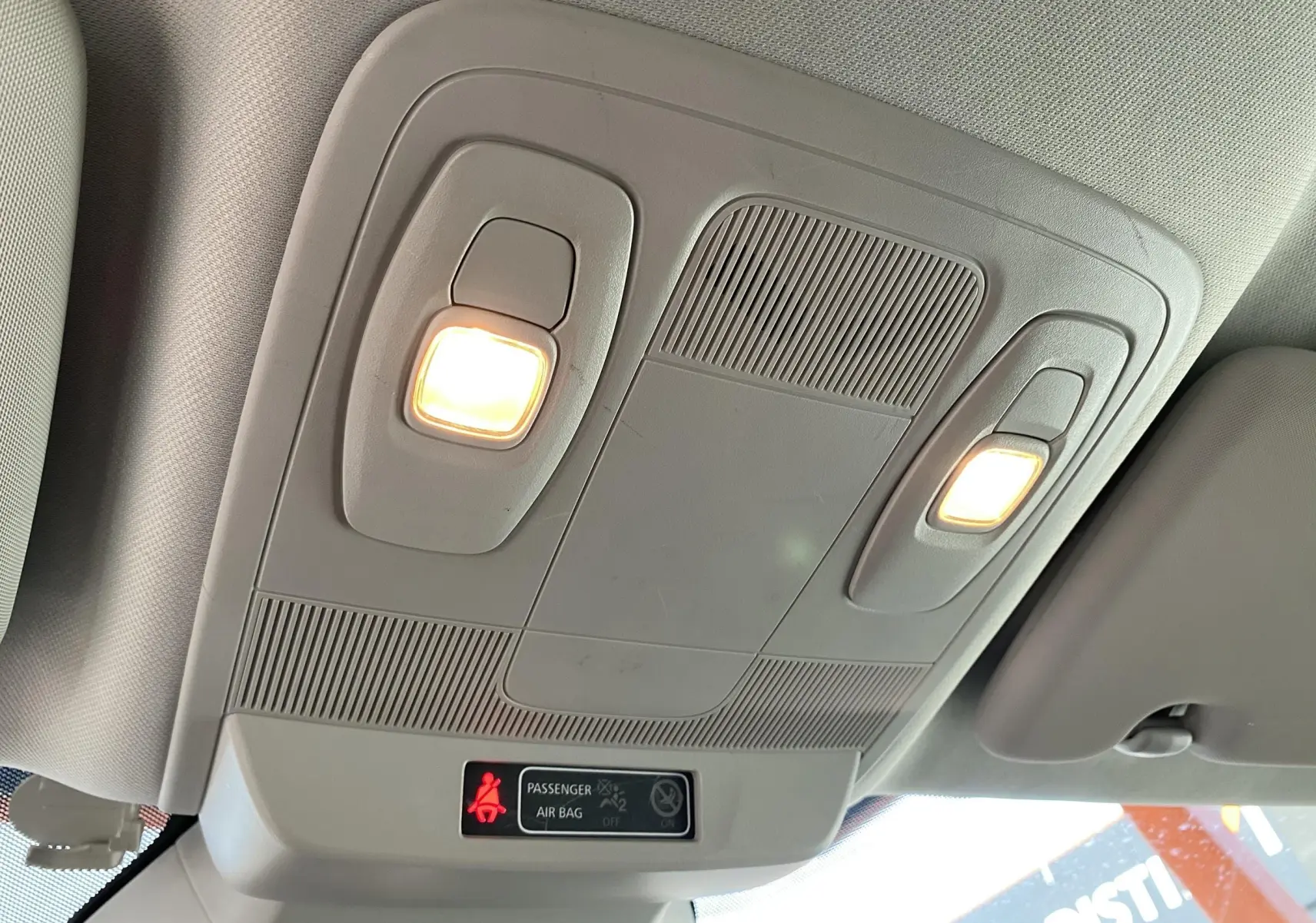 Plafonnier intérieur allumé avec indicateur d'airbag passager dans une Renault Mégane IV Berline gris, vue vers le toit.