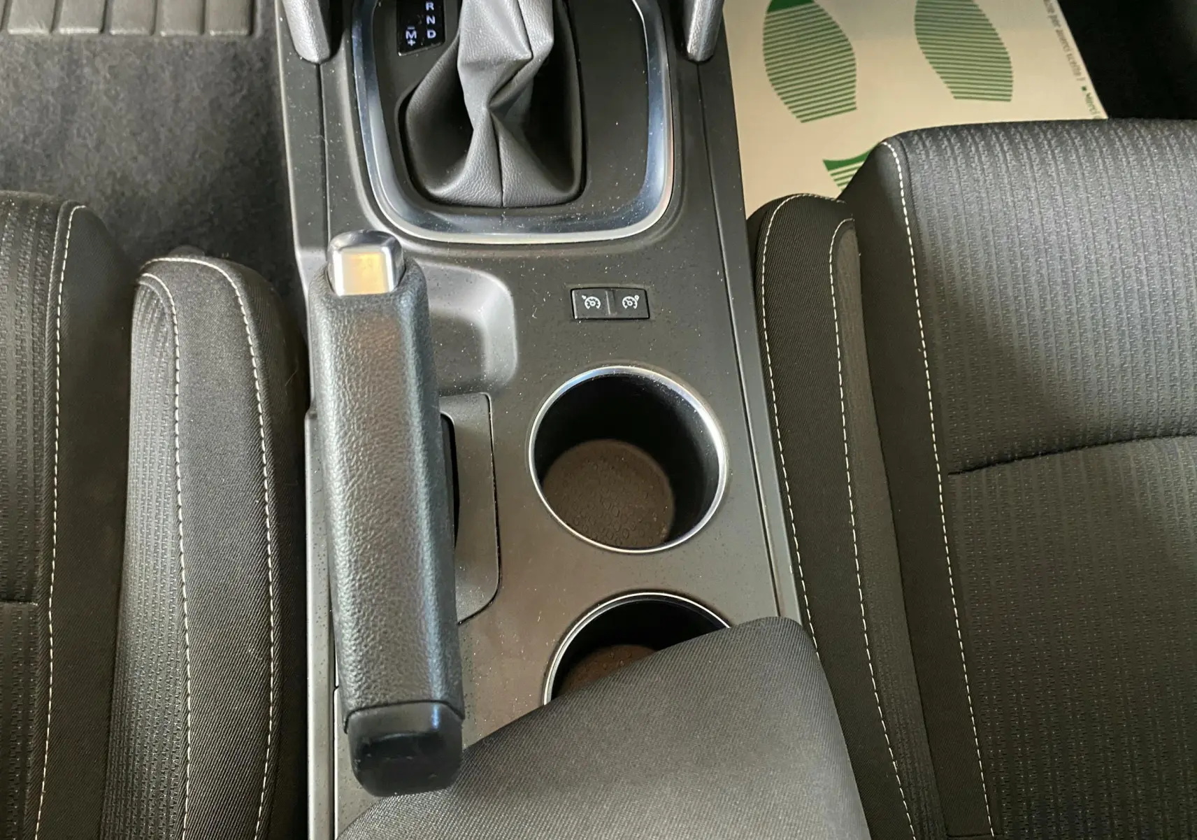 Vue plongeante sur la console centrale noire de la Renault Mégane IV avec levier de vitesse automatique et frein à main.