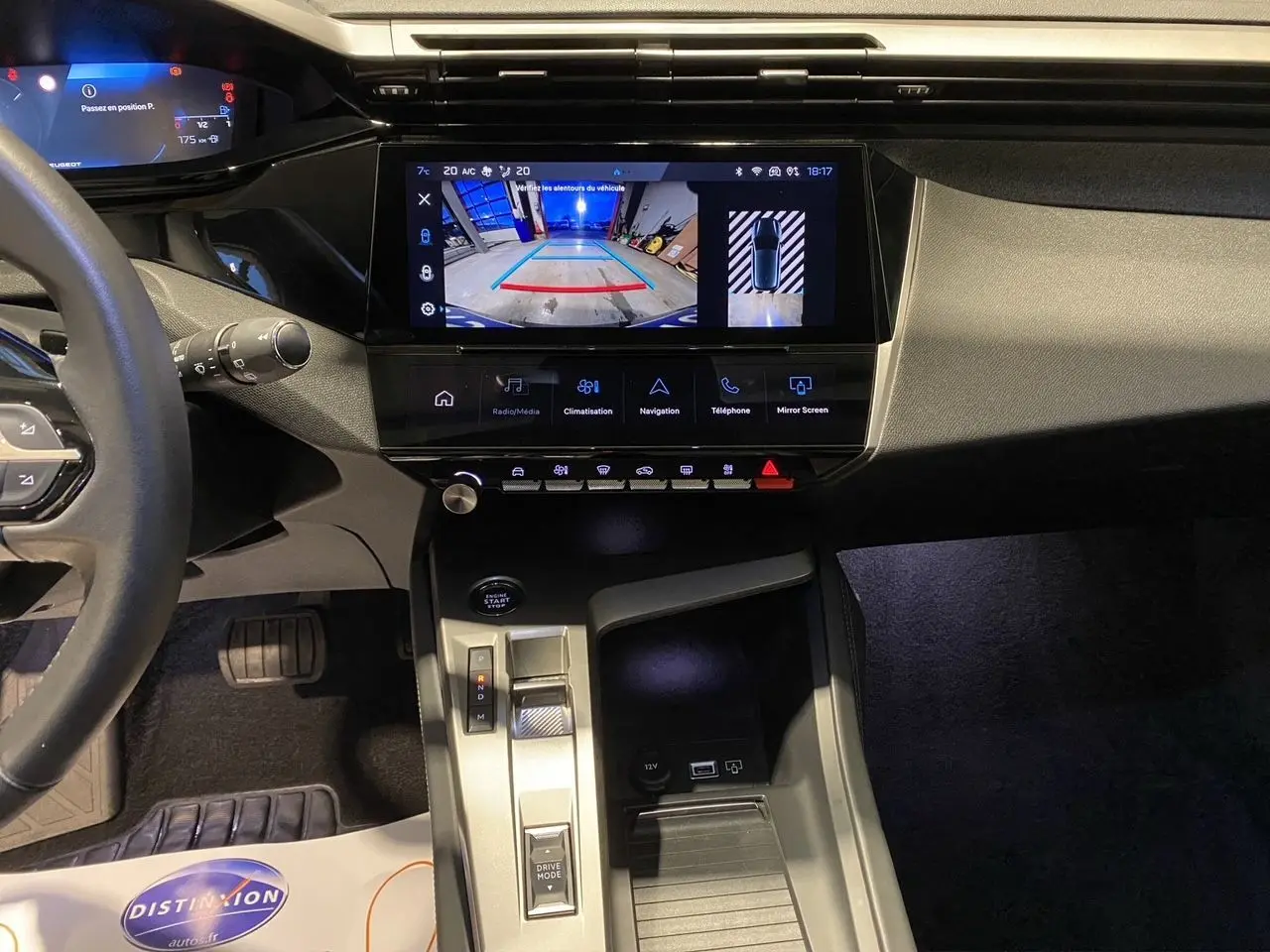 Vue intérieure du tableau de bord et console centrale de la Peugeot 308 noire, avec écran tactile affichant la caméra de recul.