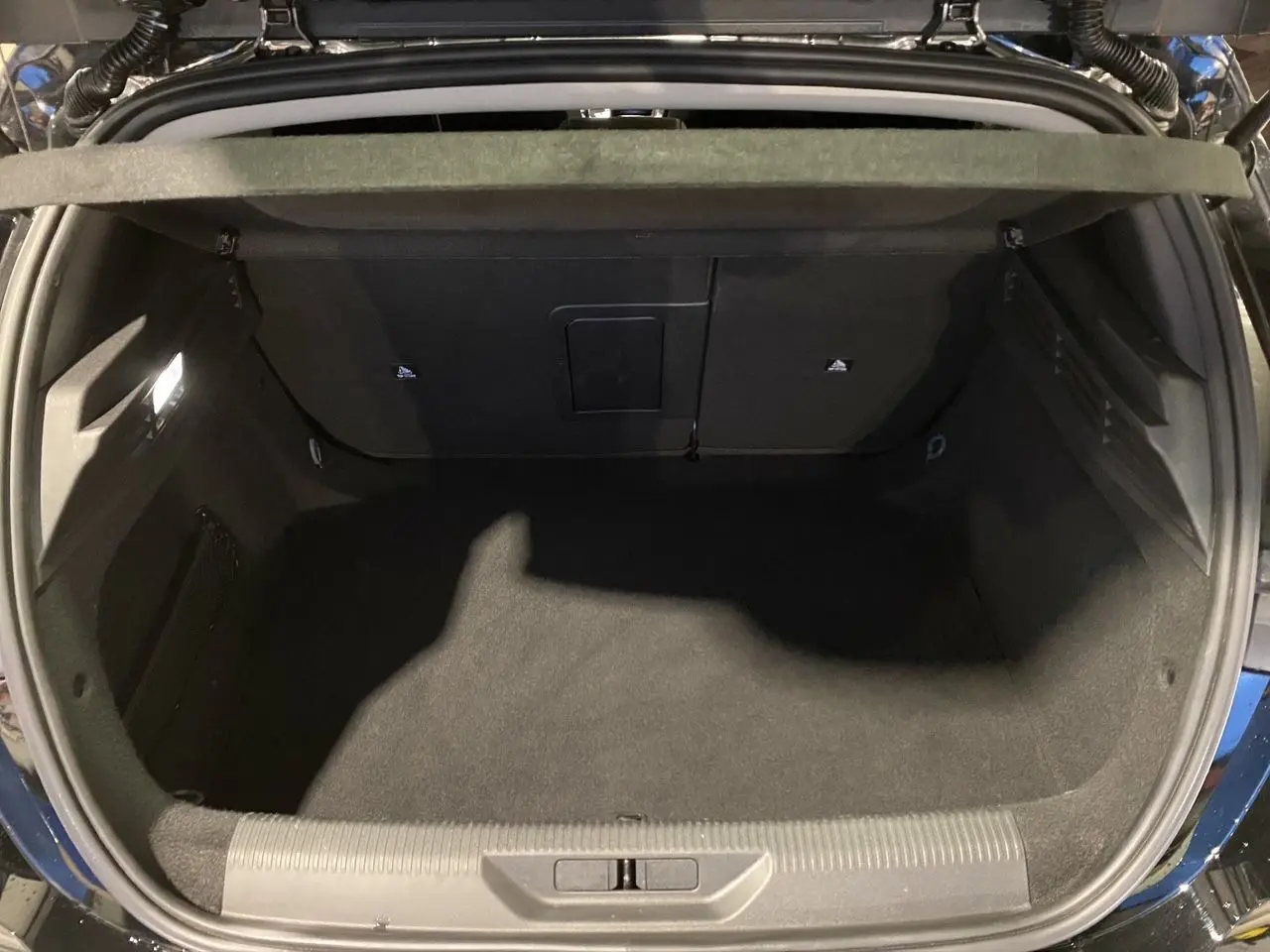 Coffre ouvert vu de dessus d'une Peugeot 308 noire Perla Nera 2024, montrant un espace de chargement propre et spacieux.