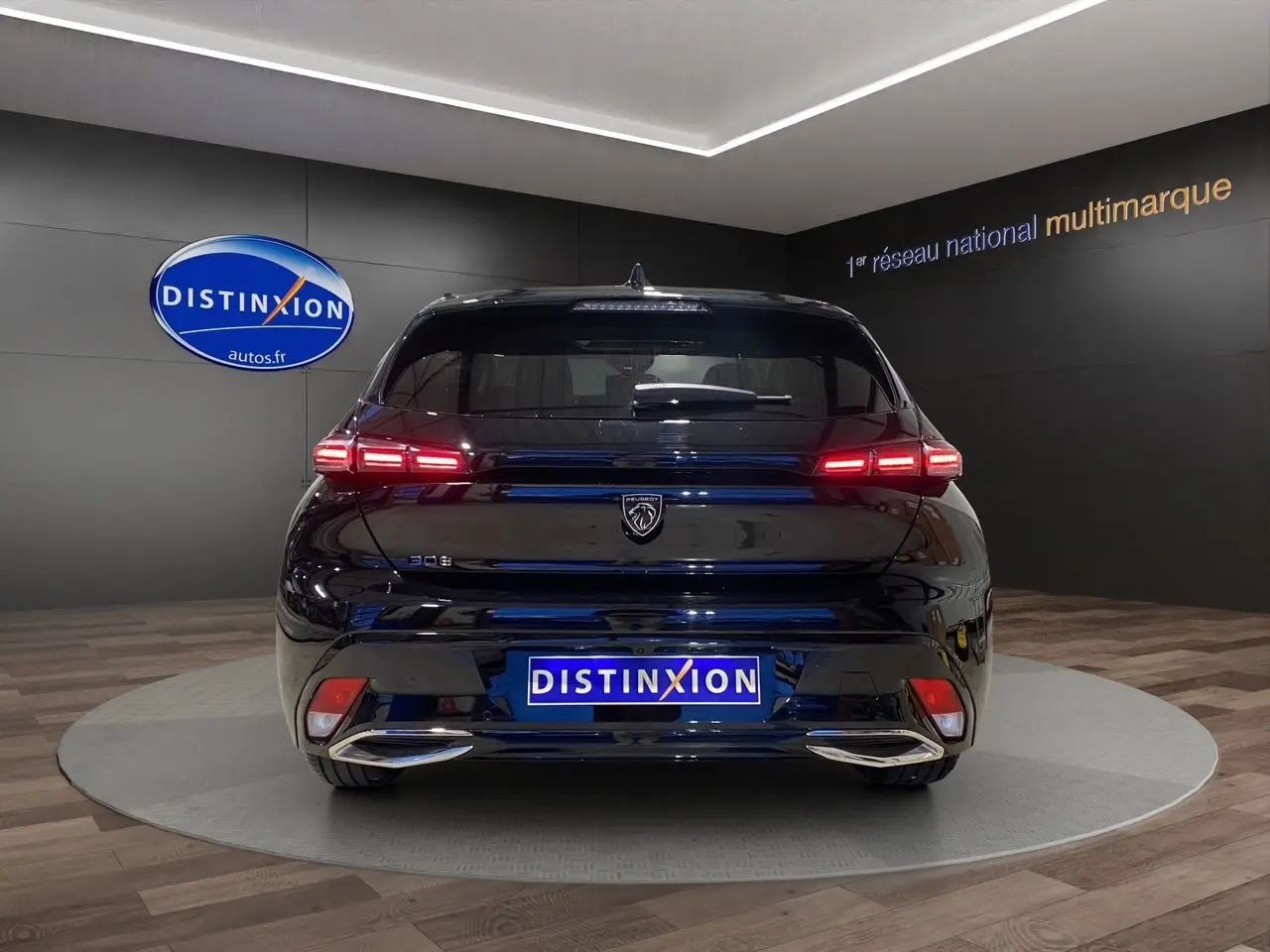 Vue arrière d'une Peugeot 308 noire Perla Nera avec feux LED allumés dans un showroom Distinxion.