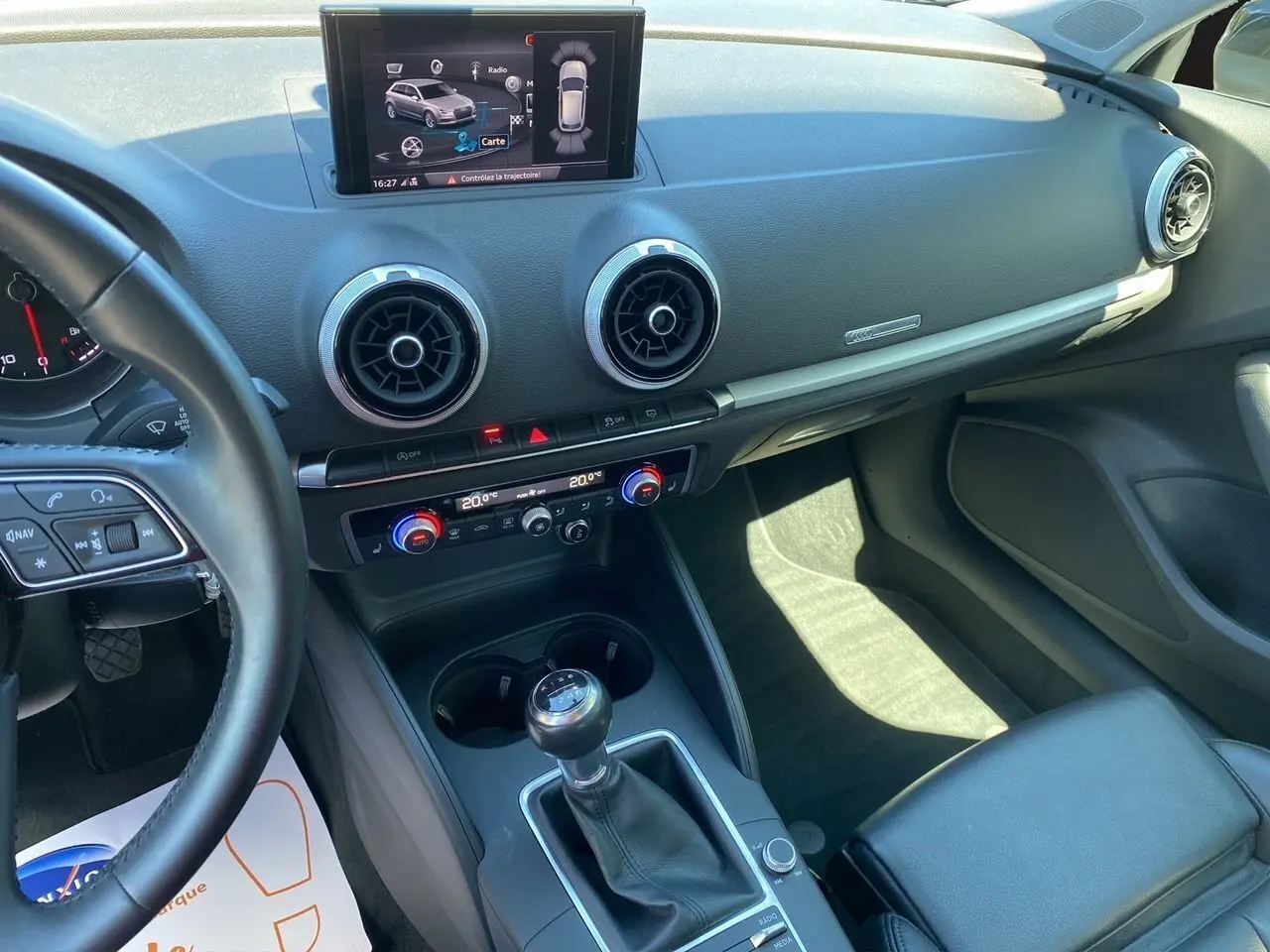 Vue intérieure côté conducteur de l'Audi A3 Sportback 2020, montrant la console centrale avec levier de vitesse manuel et écran multimédia.