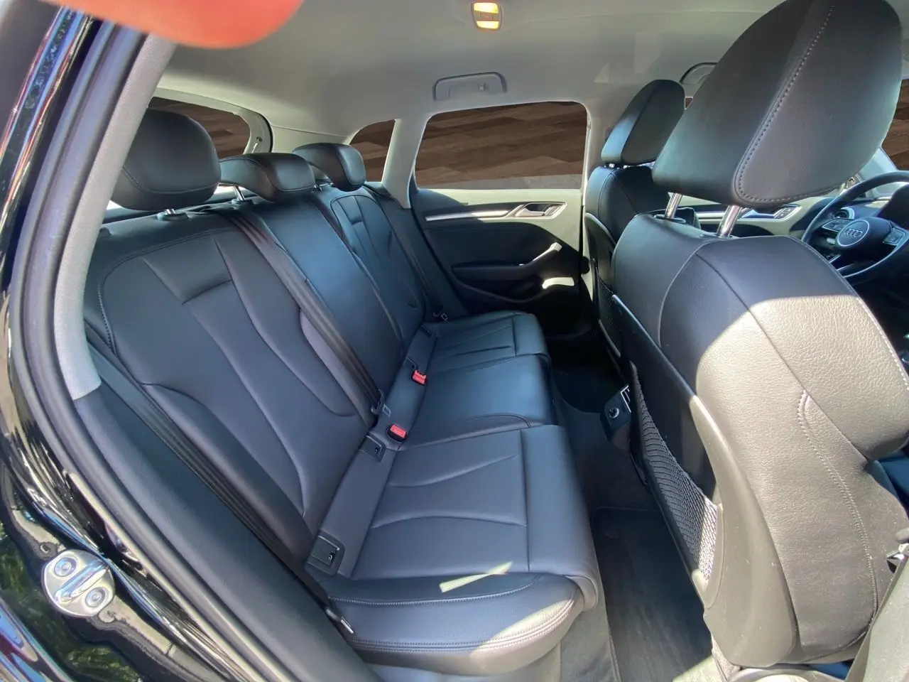 Vue intérieure arrière côté gauche d'une Audi A3 Sportback 2020 noire avec sellerie cuir noir chauffant et sièges sport.