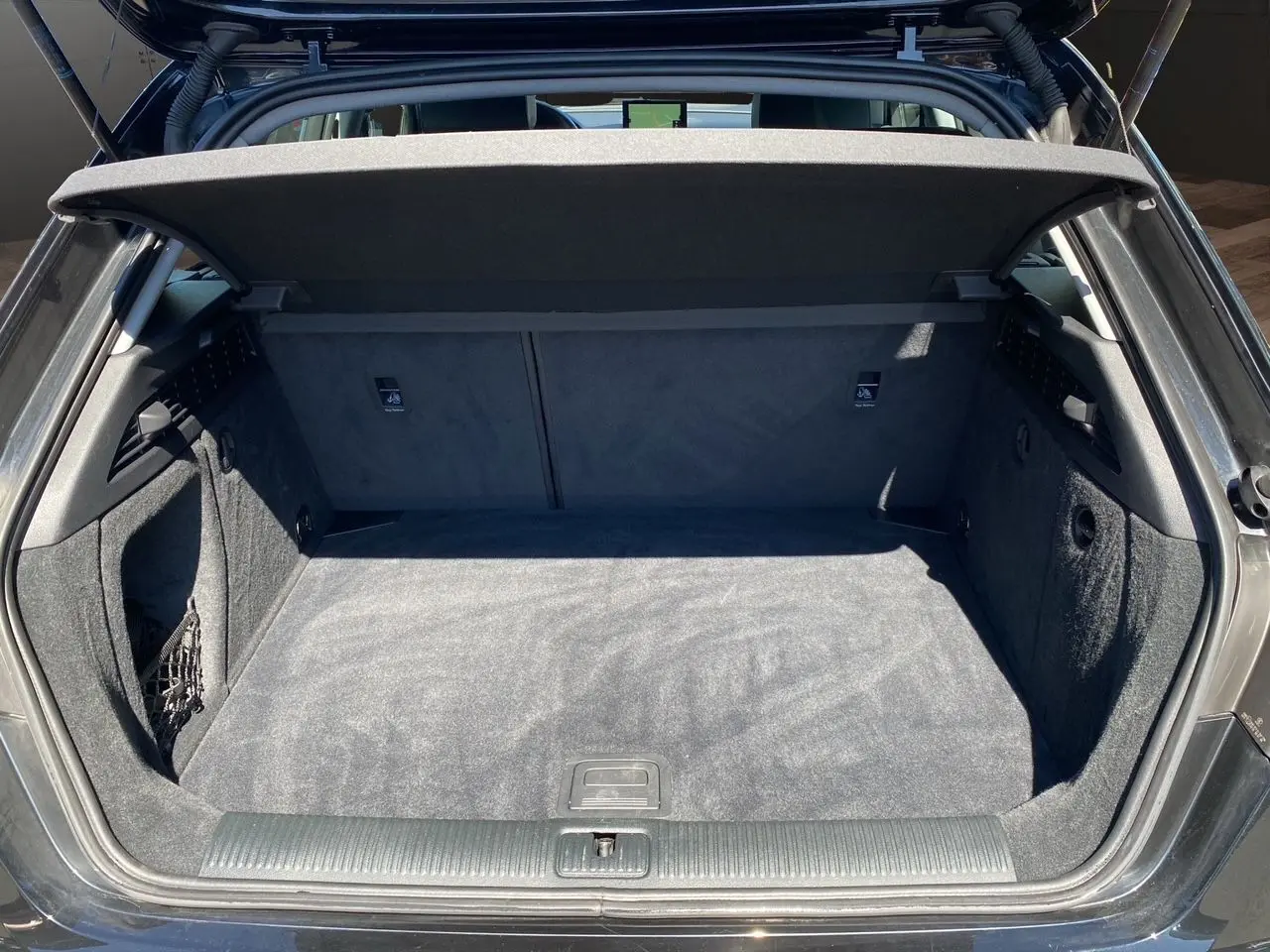 Coffre ouvert d'une Audi A3 Sportback noire, vue arrière, montrant un espace de chargement propre et bien aménagé.