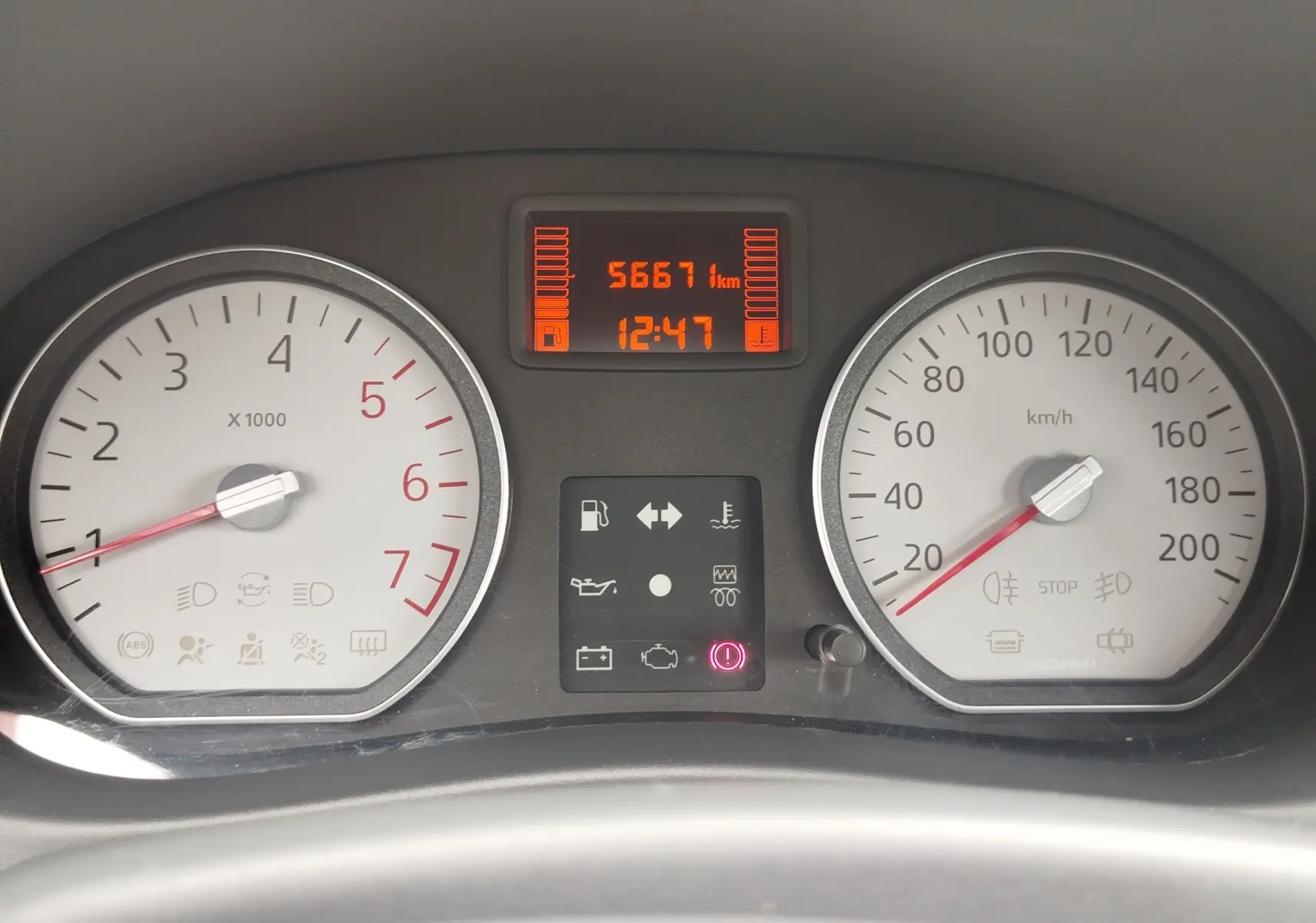 Tableau de bord de Dacia Sandero 2011, affichage digital orange avec compteur de vitesse et compte-tours blancs.