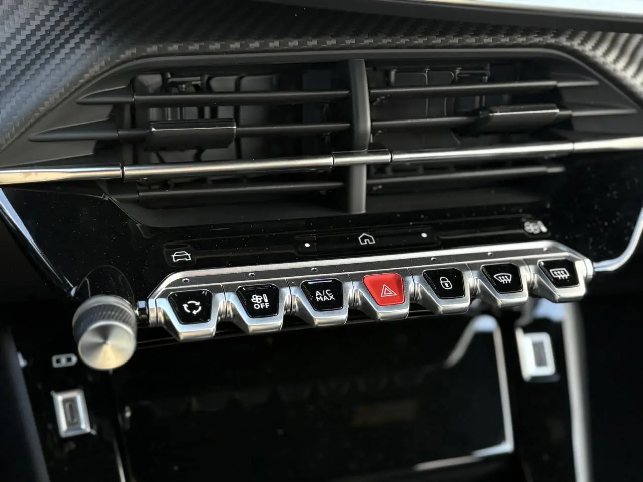 Gros plan sur la console centrale du Peugeot 2008 Hybrid 145 e-DSC6 Allure 2025, boutons argentés et rouge, finition noire brillante.
