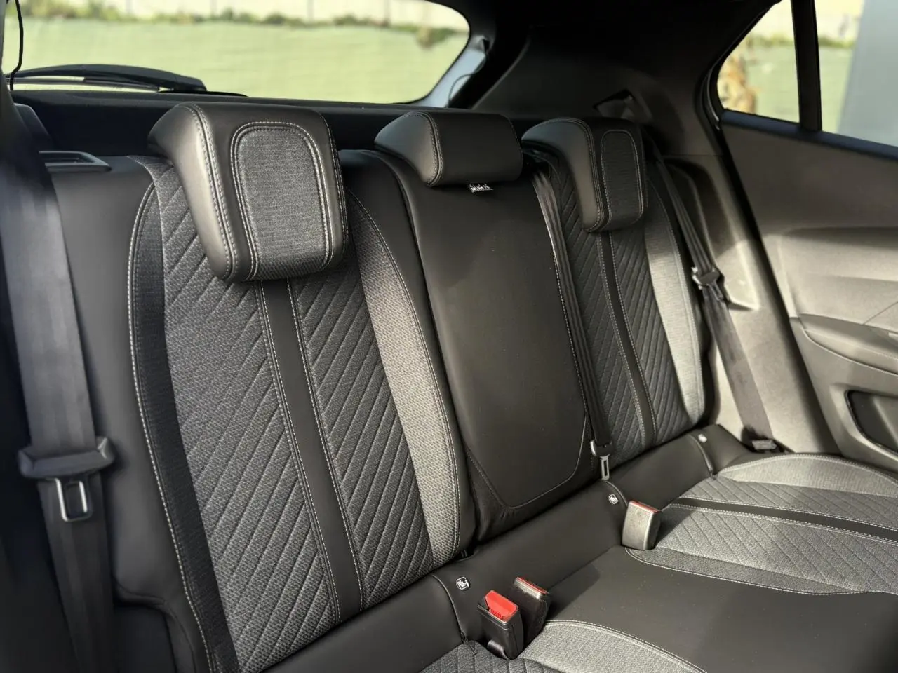 Vue rapprochée de la banquette arrière noire et grise du Peugeot 2008 Hybrid 145 e-DSC6 Allure avec appuie-têtes intégrés.