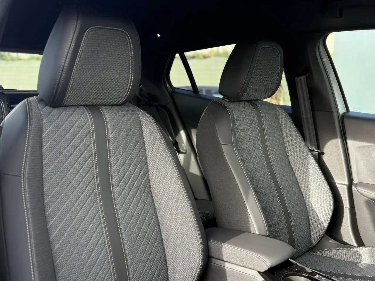 Gros plan sur les sièges avant gris et noirs du Peugeot 2008 Hybrid 145 e-DSC6 Allure, intérieur élégant et moderne.