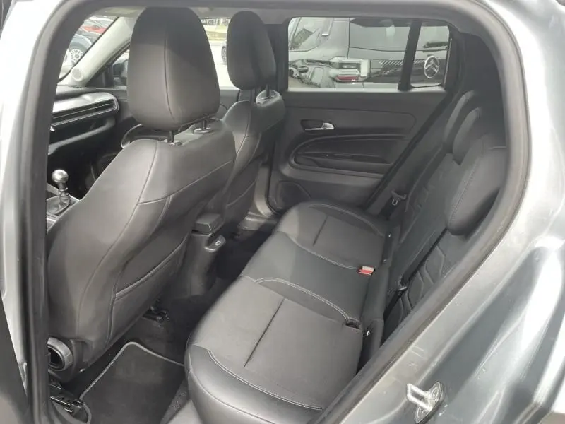 Vue intérieure arrière côté gauche du Jeep Avenger gris métal 2025, montrant les sièges arrière en tissu noir et les appuie-têtes.