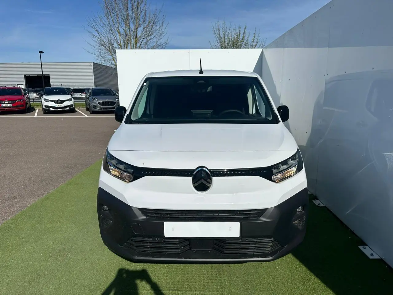 Vue de face d'un Citroën Berlingo blanc Icy avec pare-chocs noir mat et calandre épurée sur fond extérieur.