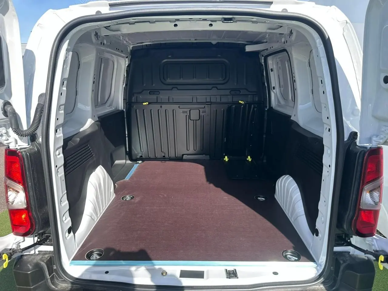 Vue arrière ouverte du Citroën Berlingo blanc Icy montrant l’espace de chargement avec plancher bois antidérapant.