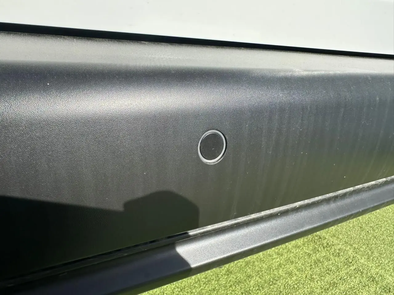 Détail du capteur de stationnement sur la porte latérale droite noire du Citroën Berlingo blanc Icy.