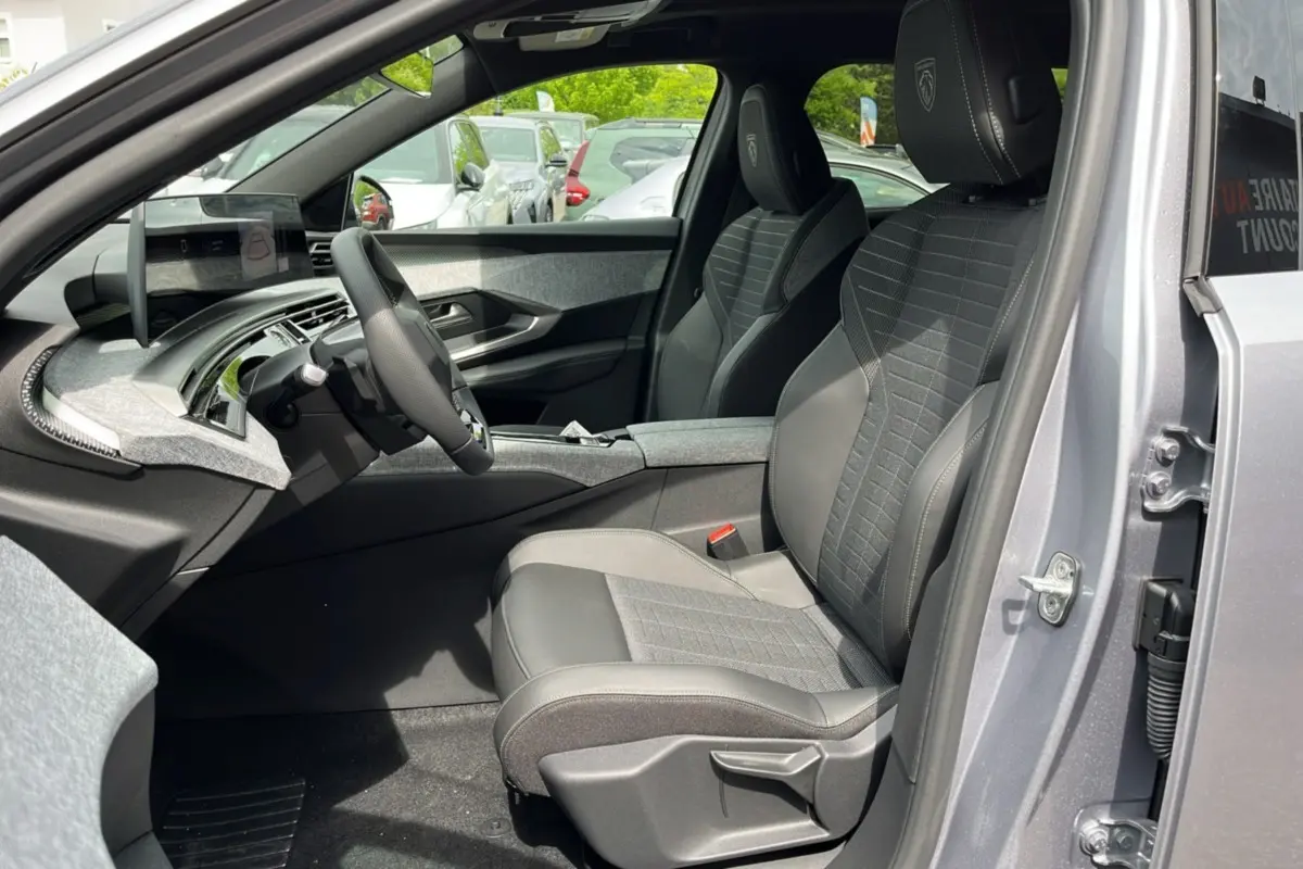 Intérieur avant droit du Peugeot 3008 New Hybrid 145 GT 360 2025, sièges en cuir gris avec logo Peugeot brodé.