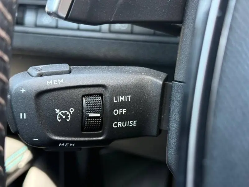 Gros plan sur la commande de régulateur de vitesse du Peugeot 3008 Hybride Rechargeable noir, avec molette et boutons MEM.