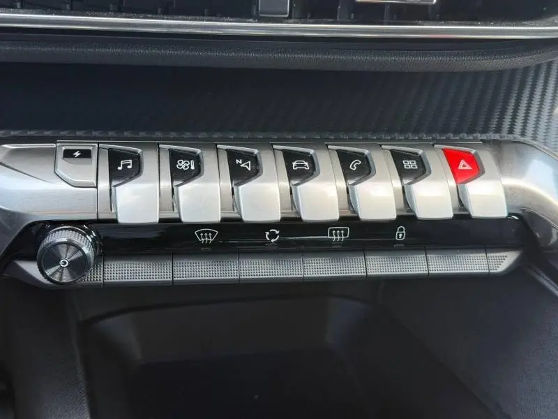 Gros plan sur la rangée de boutons argentés et noirs de la console centrale du Peugeot 3008 Hybride Rechargeable 2024.