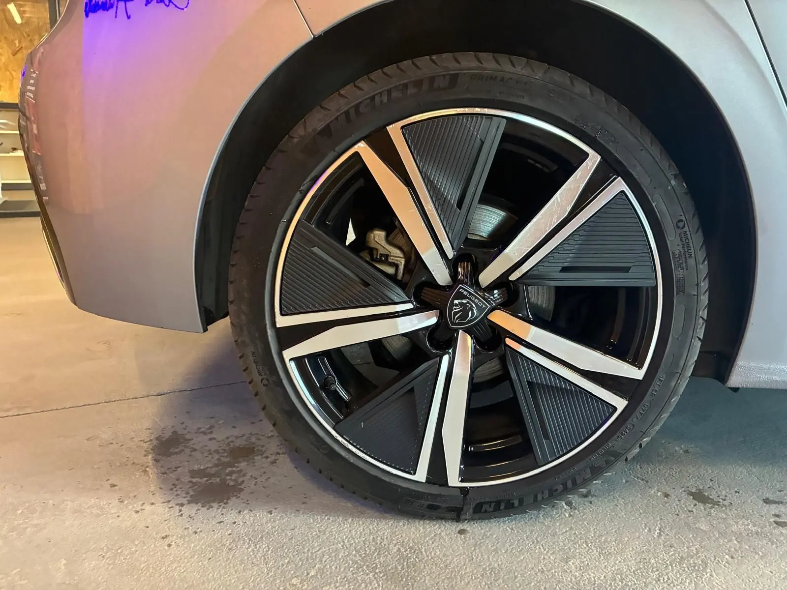 Gros plan sur la roue avant droite de la Peugeot 308 gris 2025, mettant en valeur la jante noire et argentée au design moderne.