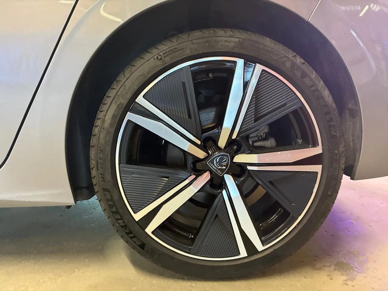 Gros plan sur la roue avant droite gris métallisé d'une Peugeot 308 1.2 Hybrid 136 E-DCS6 GT avec jante noire et argent.