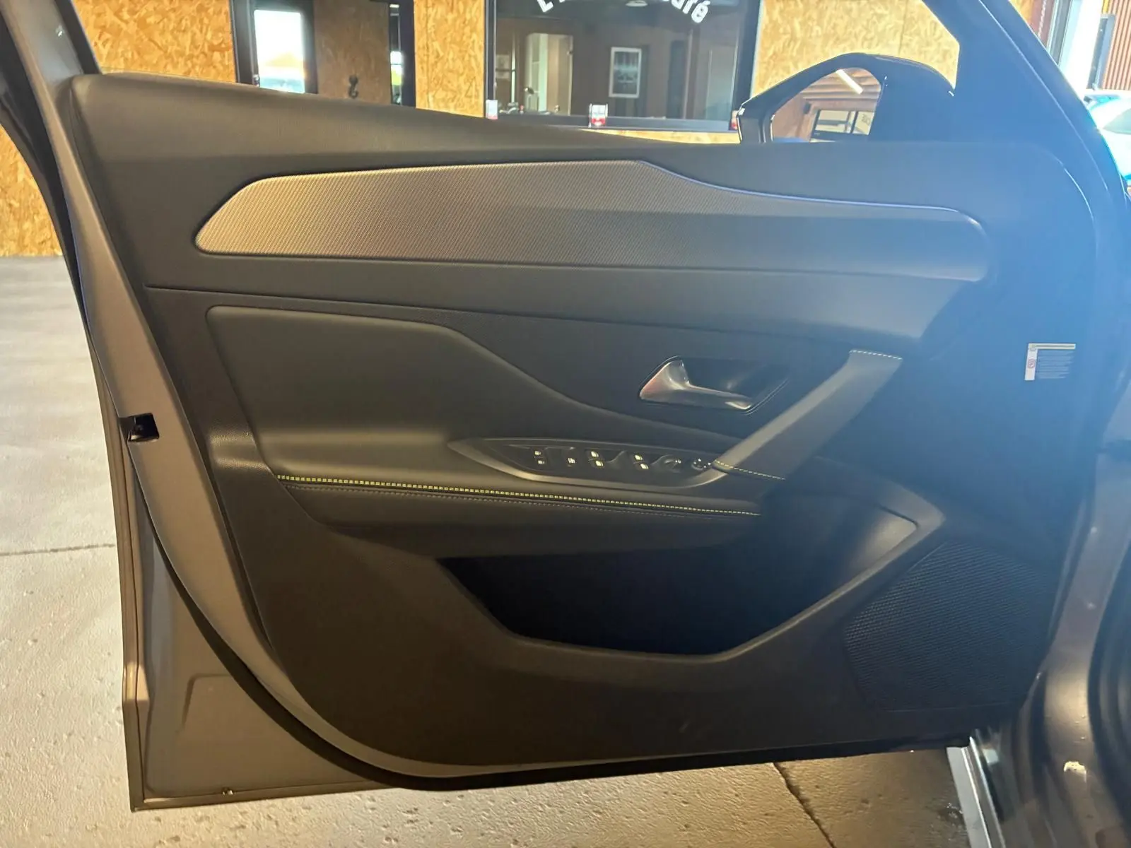 Vue rapprochée de la porte avant gauche gris métallisé de la Peugeot 308 1.2 Hybrid 136 E-DCS6 GT avec commandes de vitres et haut-parleur intégré.