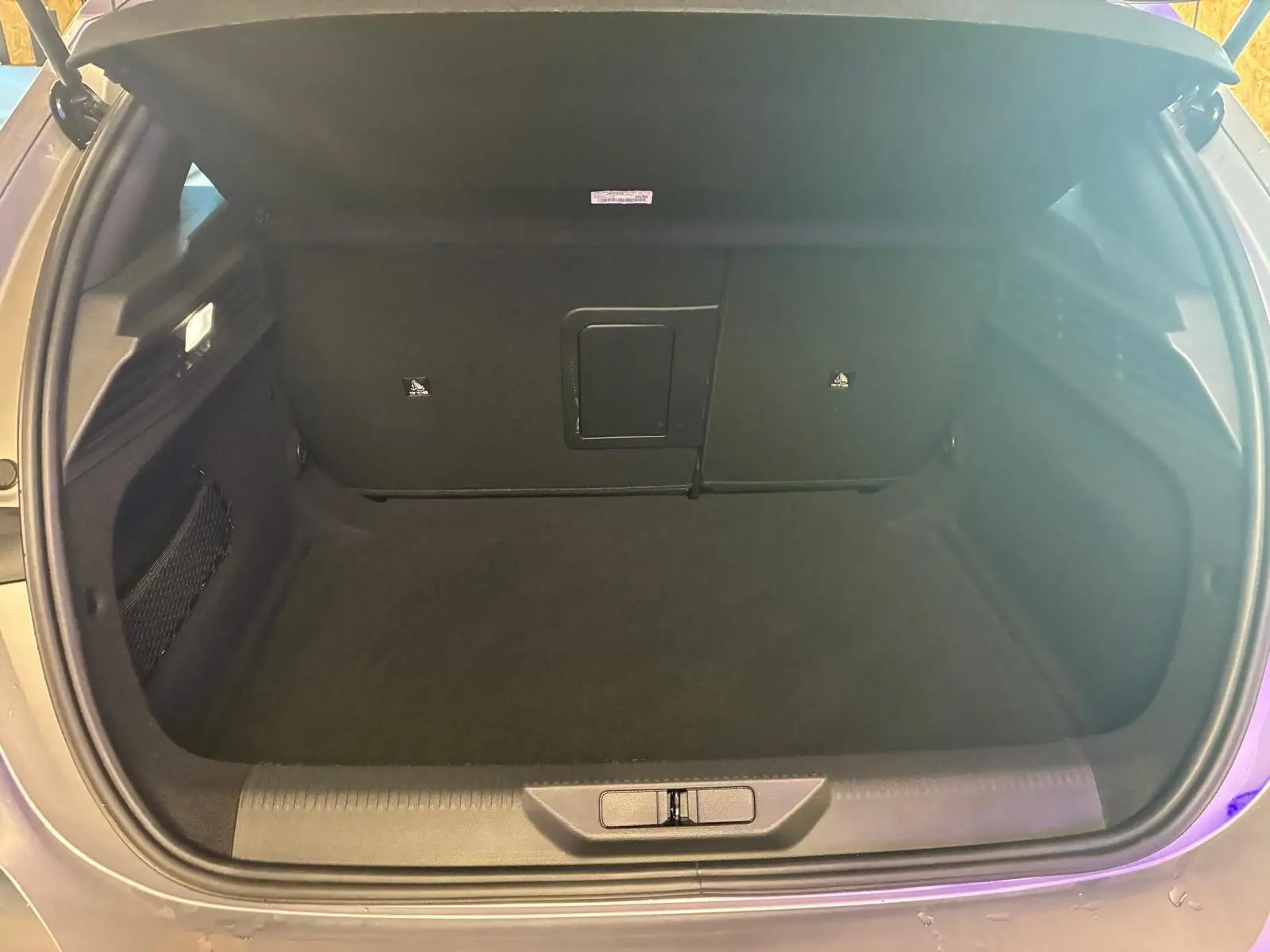 Coffre ouvert de la Peugeot 308 gris, vue de dessus montrant l’espace de rangement intérieur vide.