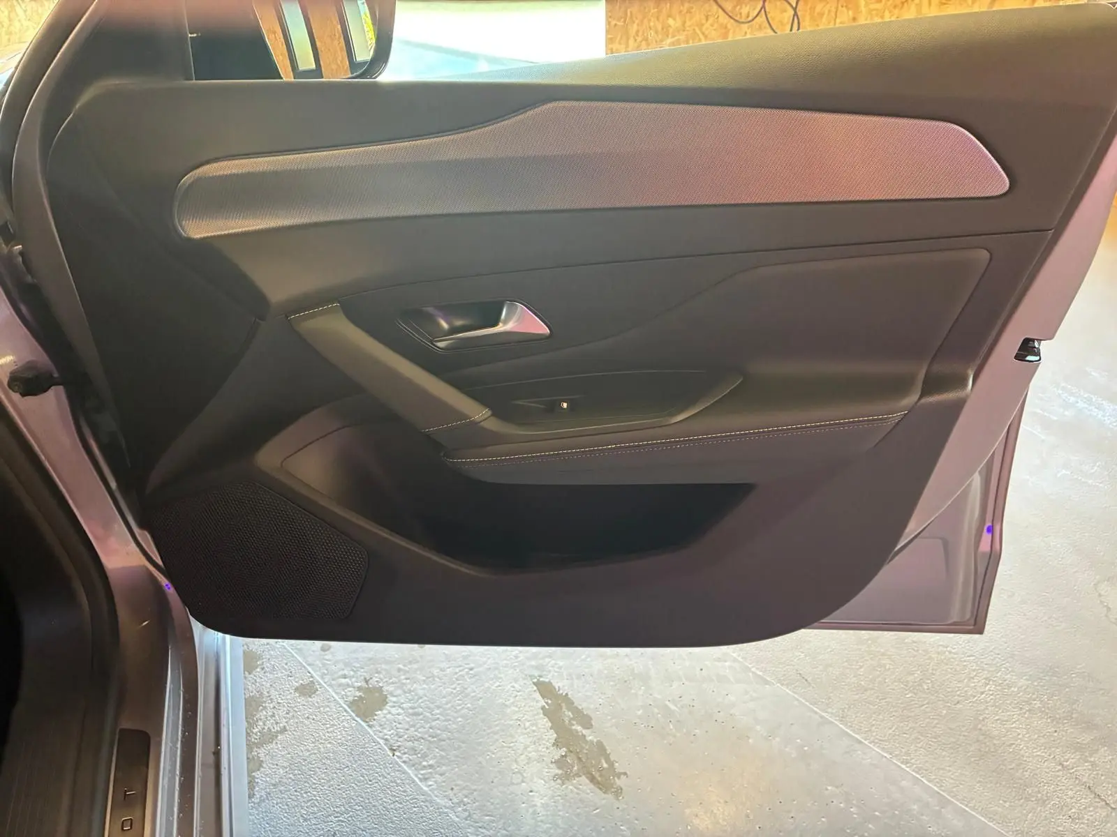 Vue intérieure de la porte avant gauche grise de la Peugeot 308 1.2 Hybrid 136 GT avec garniture noire et insert texturé.