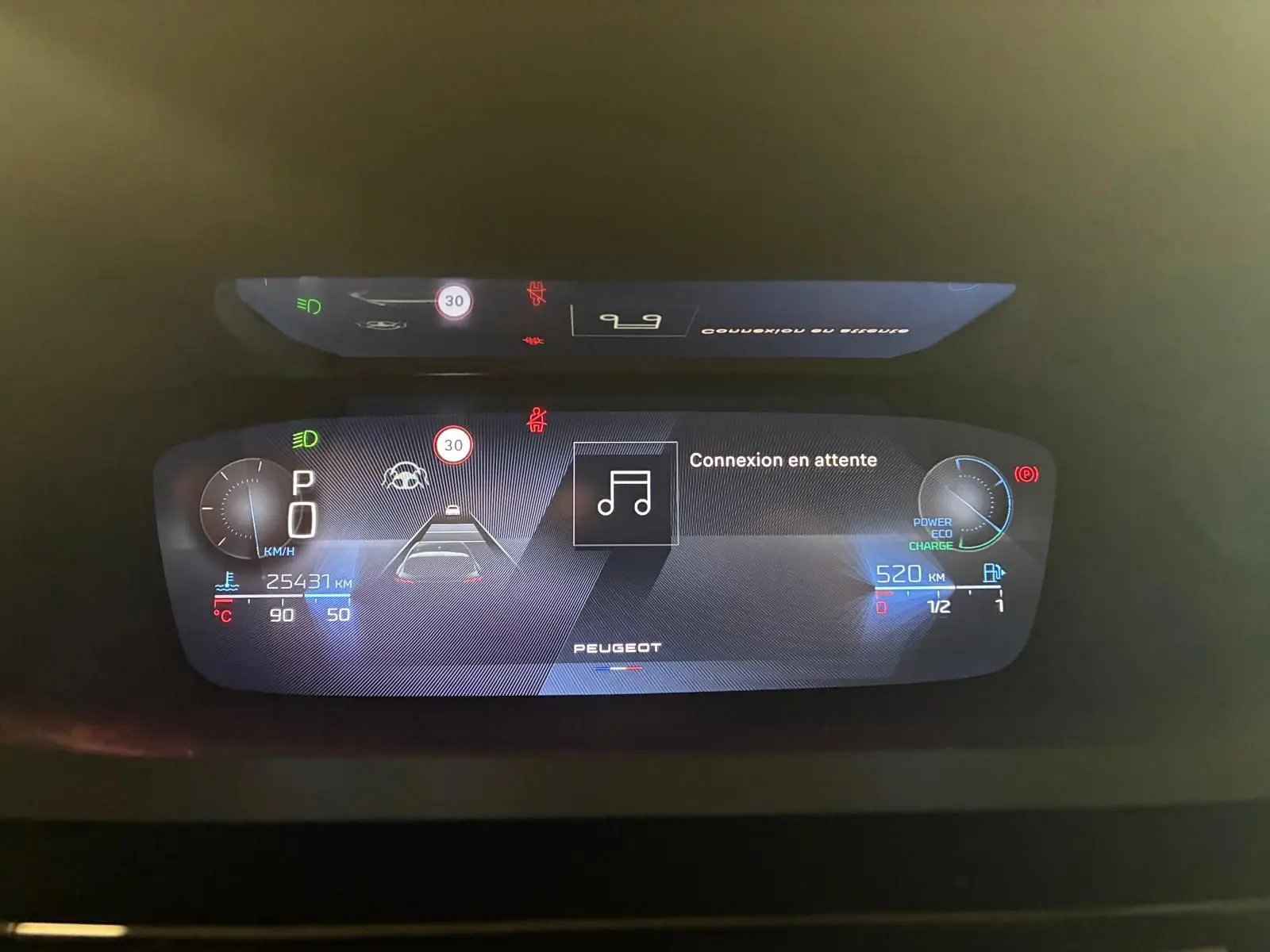 Tableau de bord numérique de la Peugeot 308 gris, affichant la vitesse, autonomie et alertes en vue frontale rapprochée.