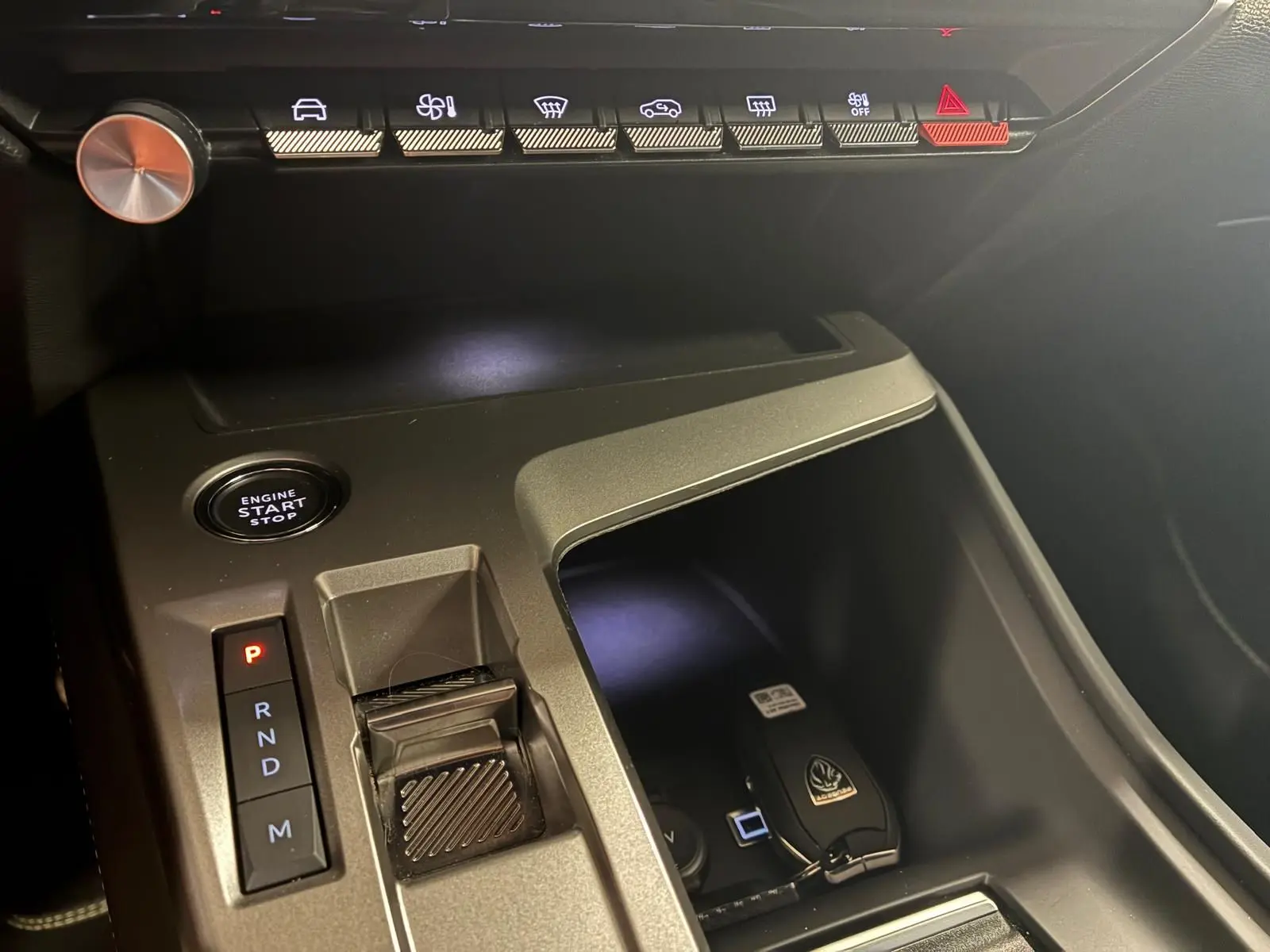 Vue rapprochée de la console centrale noire de la Peugeot 308 hybride 2025 avec sélecteur de vitesse et bouton start/stop.