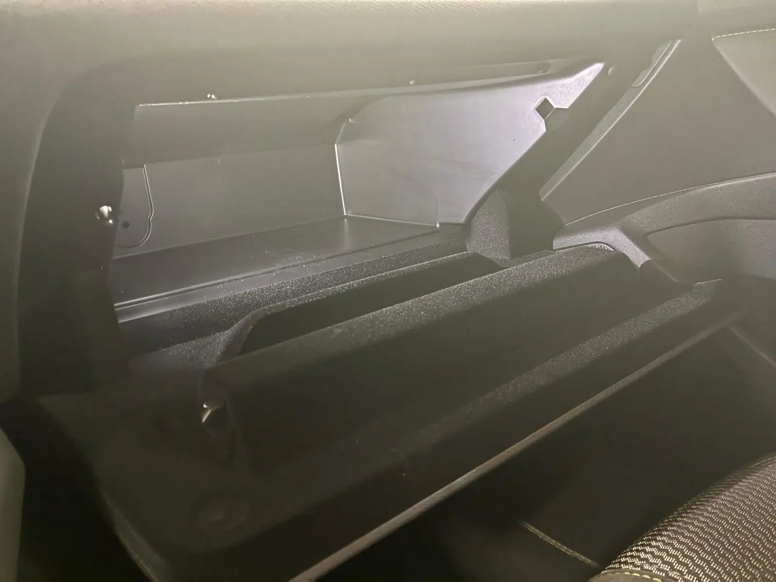Vue rapprochée de la boîte à gants ouverte du Peugeot 308 gris 1.2 Hybrid 136 E-DCS6 GT, intérieur noir.