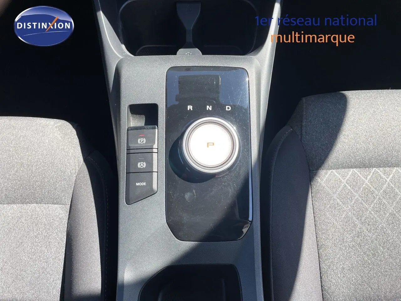 Vue plongeante sur la console centrale du MG3 2025 en tissu gris, avec sélecteur rotatif de boîte auto et boutons de contrôle.