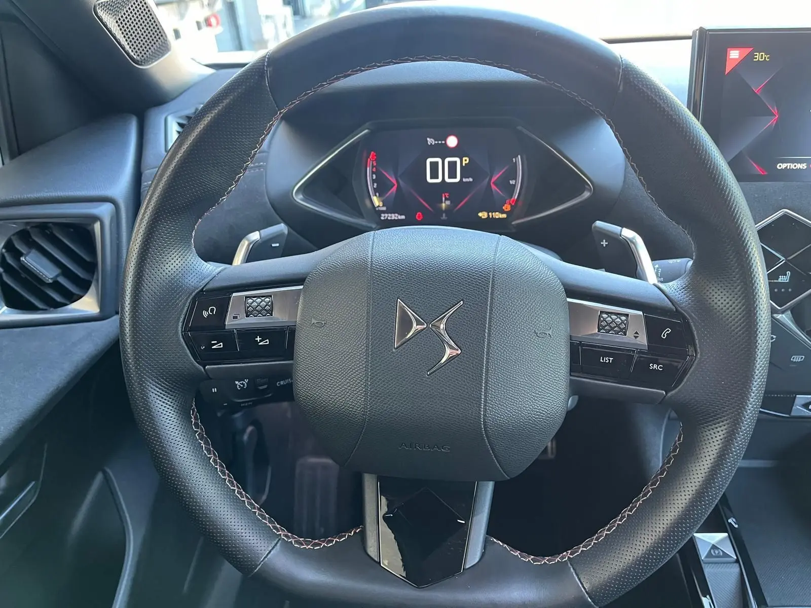 Vue rapprochée du volant DS Performance Line en cuir noir avec commandes intégrées et tableau de bord numérique.